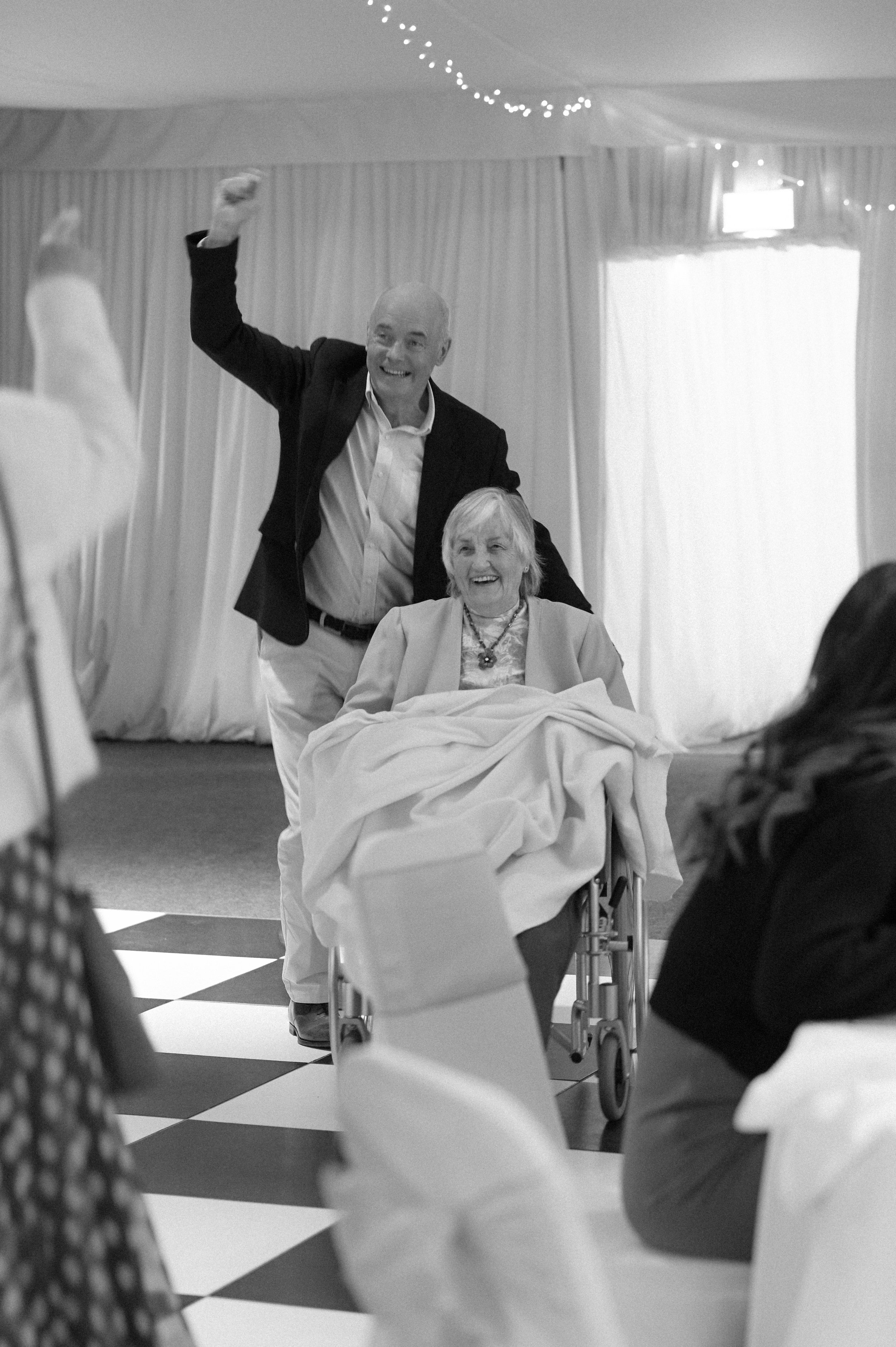 A black and white photograph at Broome Park Hotel of two guests, a white man and woman, dancing on the dance floor. They are both laughing.