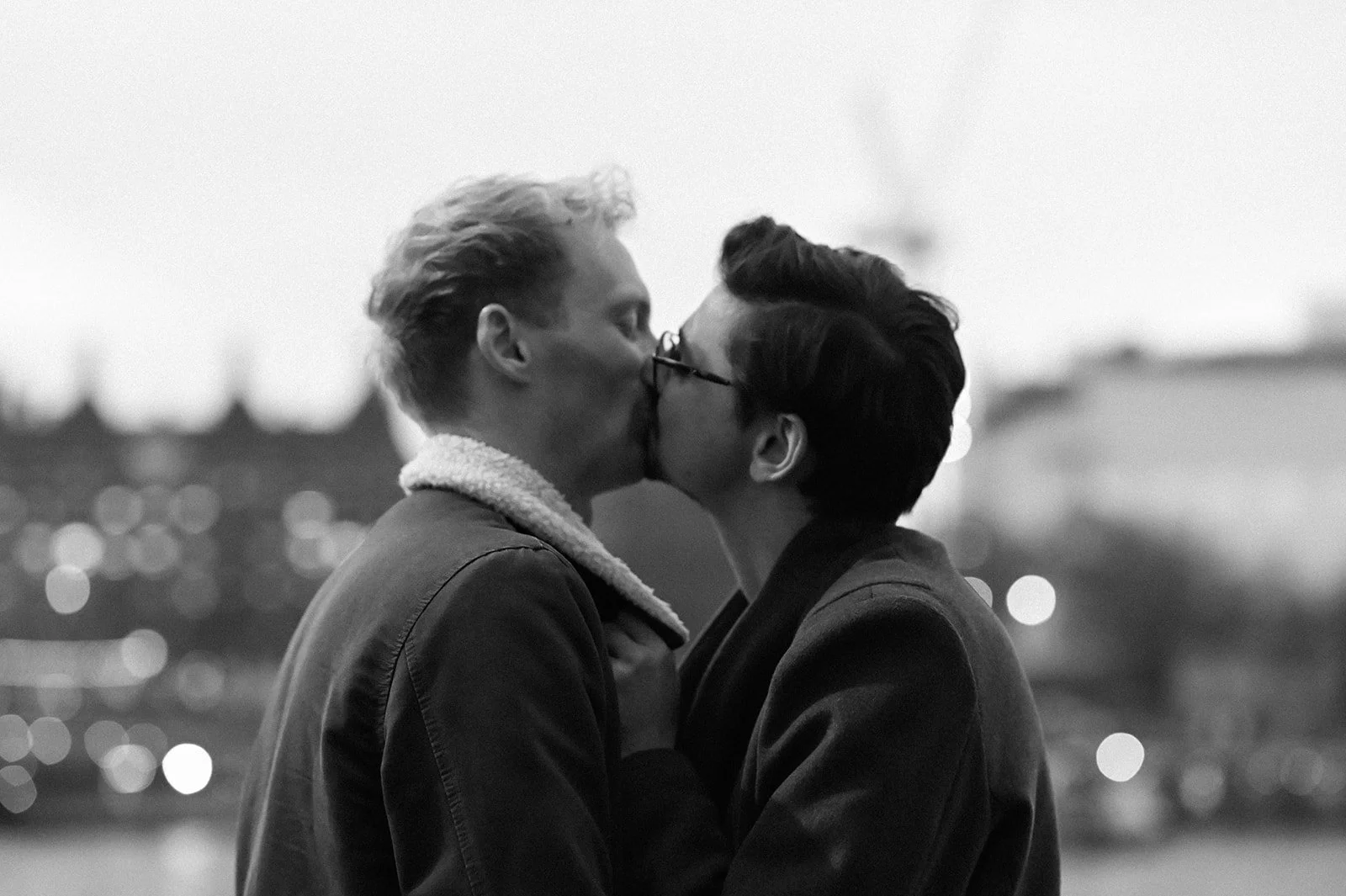 A black and white photograph on London's Southbank of a couple, two white men, kissing. Their eyes are closed and they are lost in the moment.
