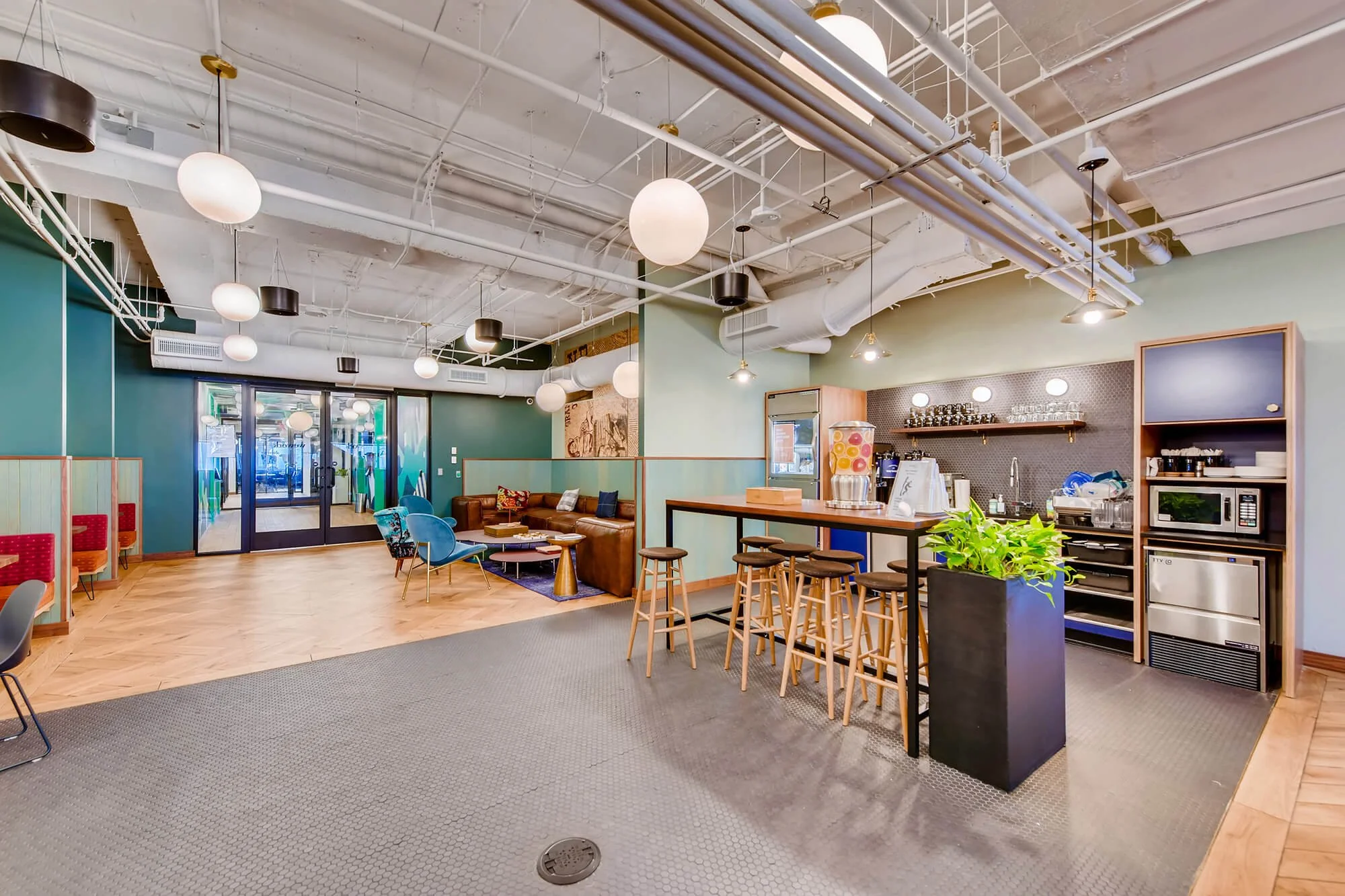  Open-plan office lounge with exposed ceiling, seating area, a coffee bar, and a juice dispenser. 