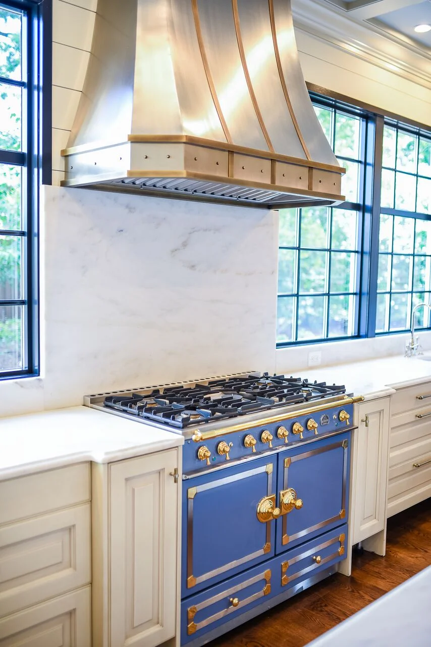 Handcrafted metal range hood by Raw Urth Designs and 43” LaCornue® French range in Provence blue finish with elegant brass knobs