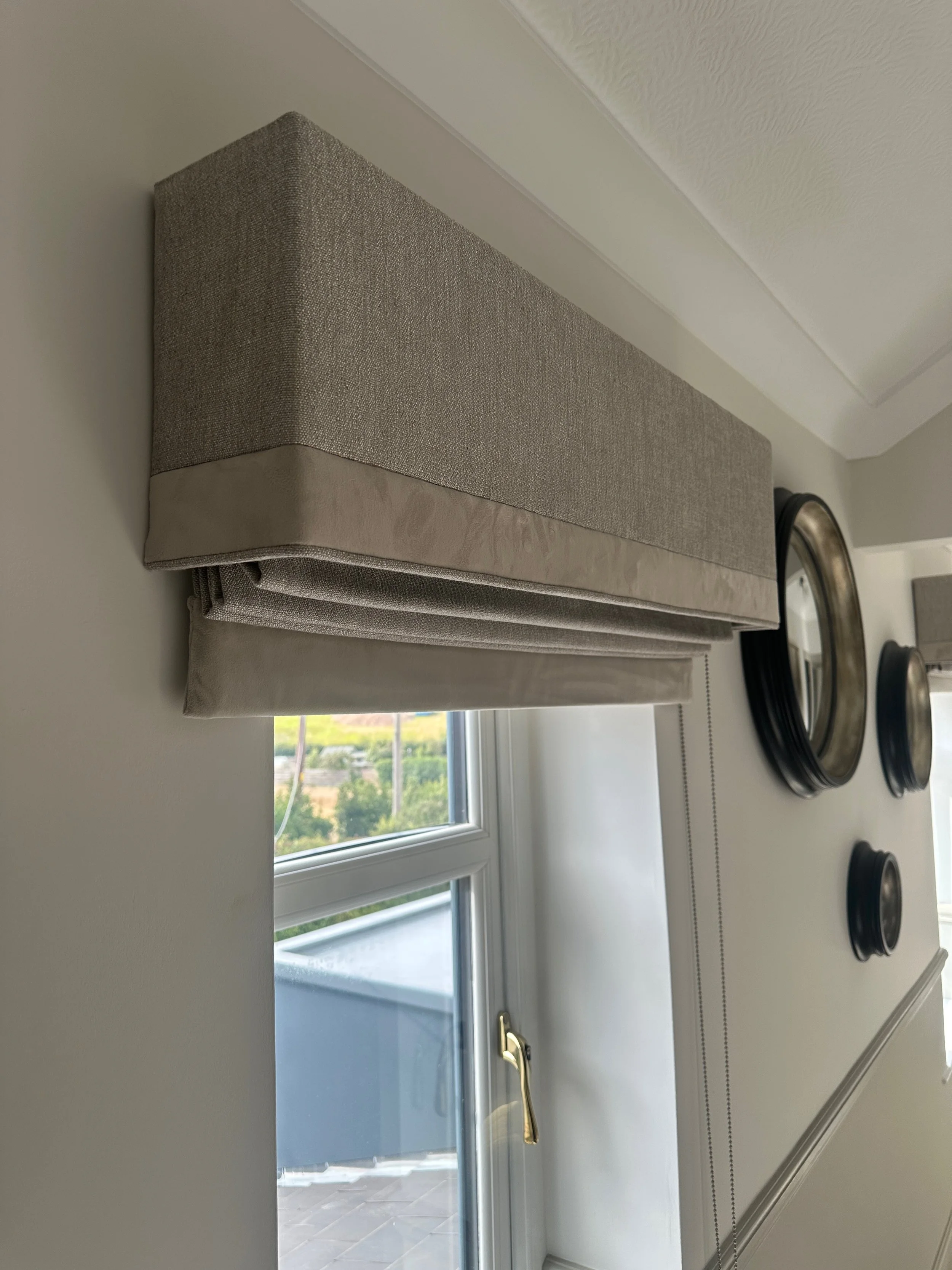 Decorative window valance above a sliding glass door, with three round wall mirrors to the right and a glimpse of a balcony outside.