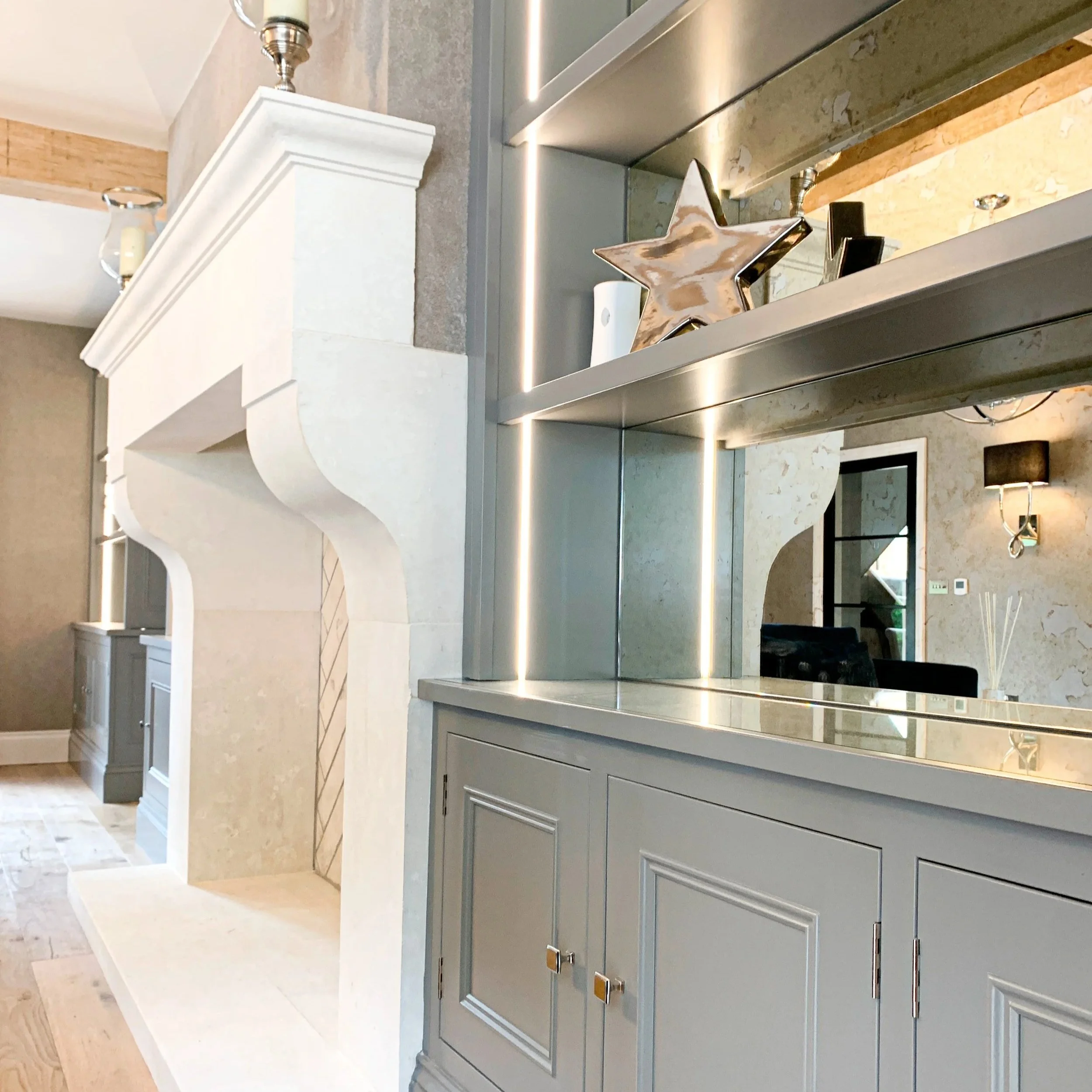 Interior of a modern home with a fireplace, decorative shelving with a star-shaped ornament, and a mirror reflecting a dining area.