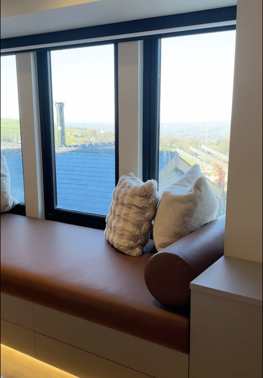 A window seat with pillows overlooking a scenic view of the landscape and sky outside.