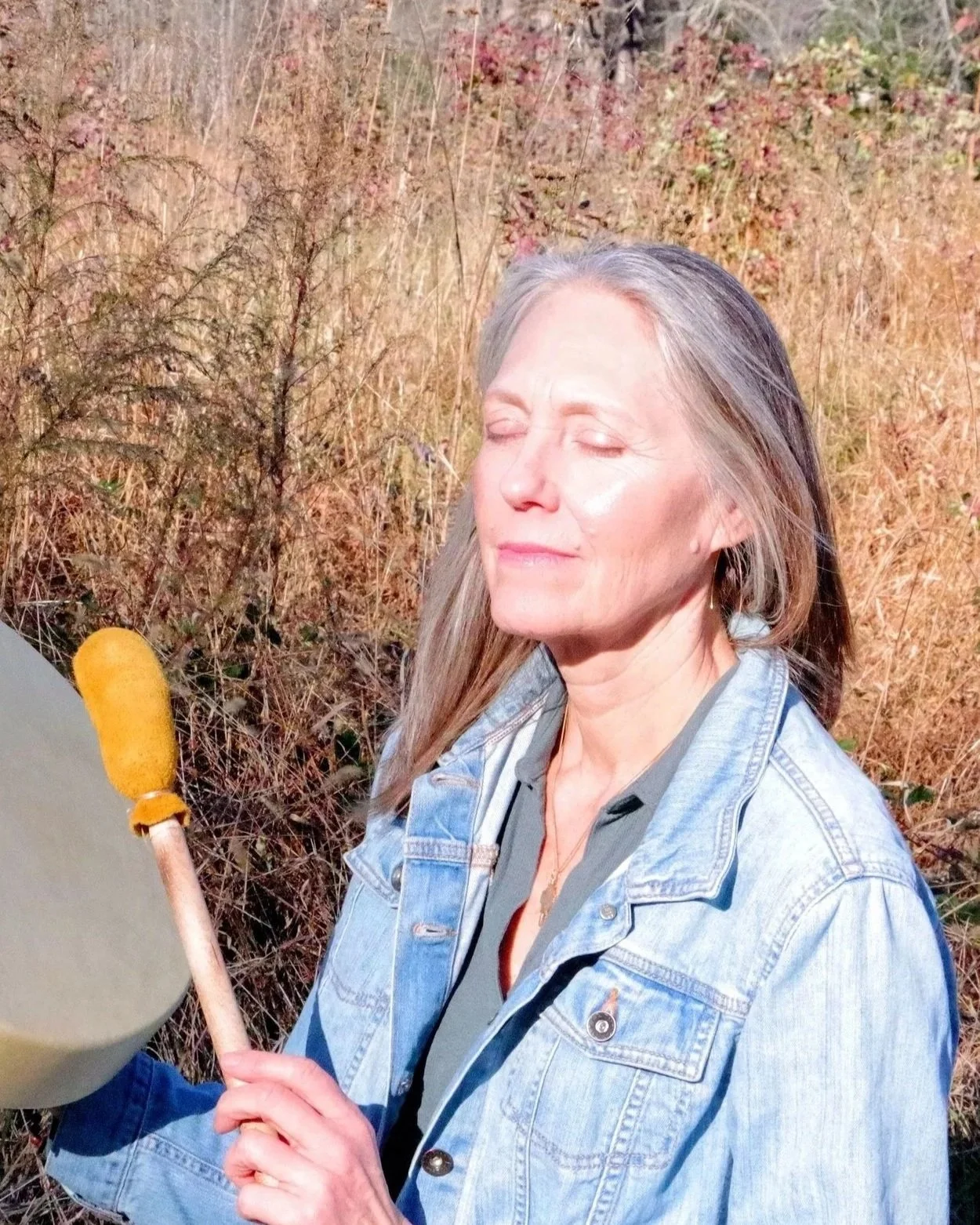 Somatic and energy healer Diane stakoe outdoors with a drum during a sound healing session in Raleigh, North Carolina