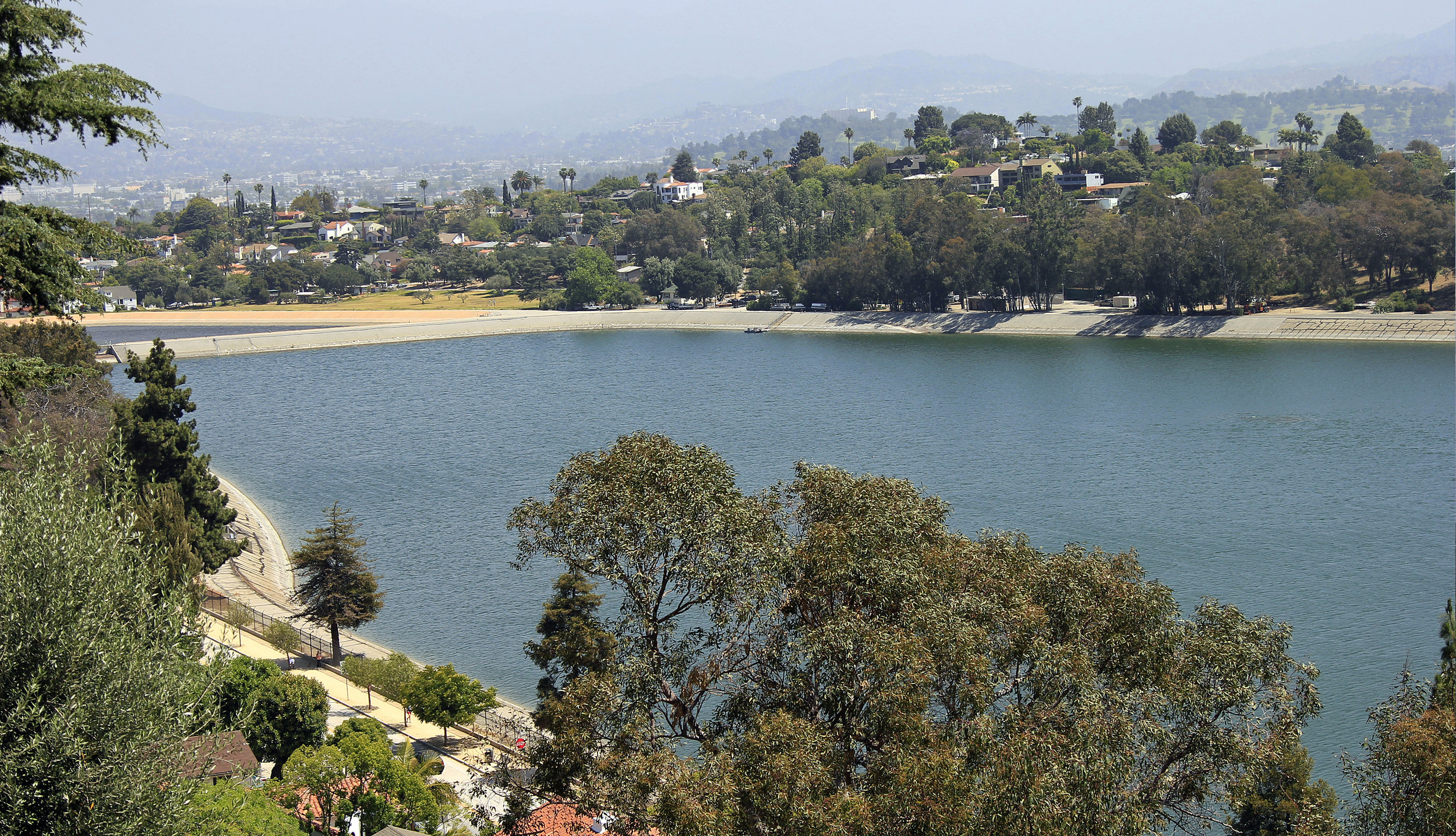 The shimmering reflection of the Silver Lake Reservoir and its hilly, surrounding neighborhood. The Angeles National Forest in the San Gabriel Mountain range is seen in the distance. Learn more about Silver Lake...