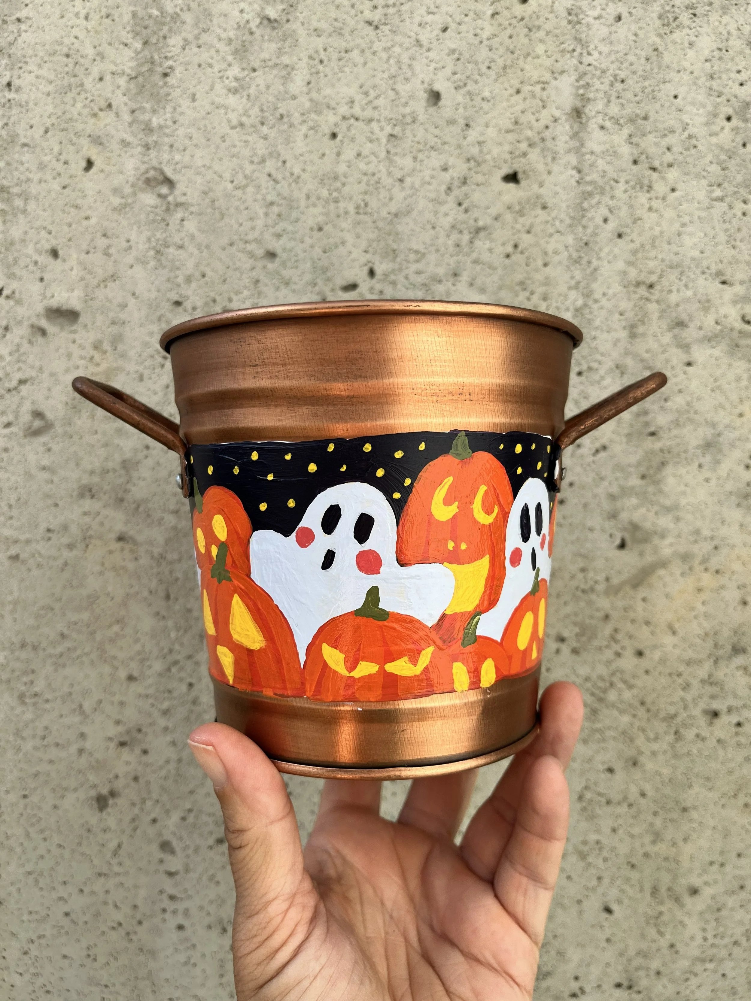 Hand painted Halloween copper color bucket. Painted with a variety of spooky ghosts and carved jack o lanterns.