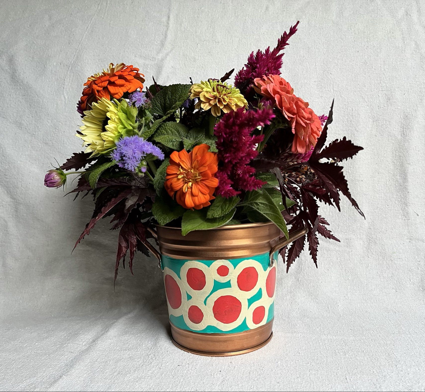 Decorative copper color tin bucket with mod circles painted on. Red, white and blue