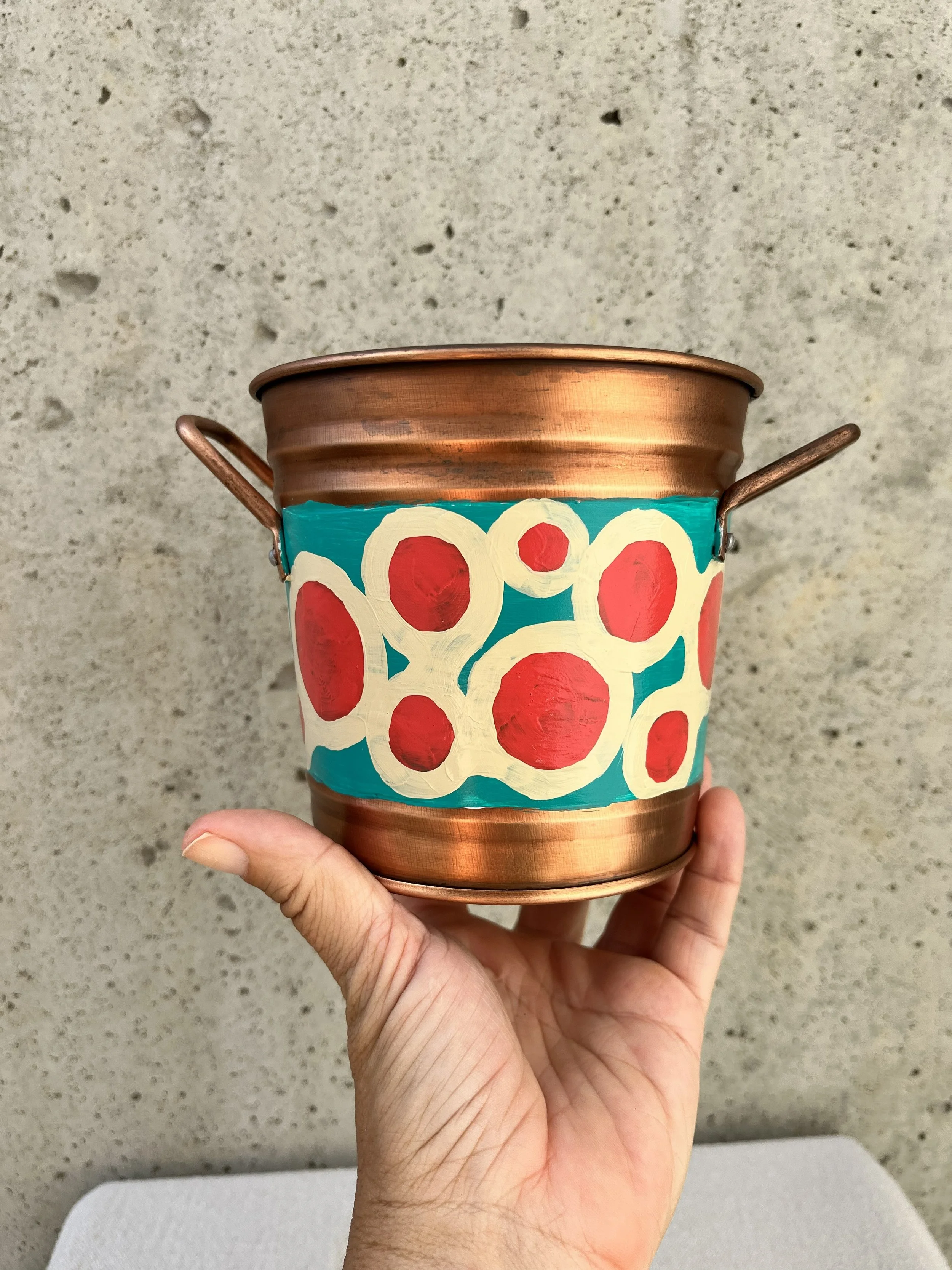 Decorative copper color tin bucket with mod circles painted on. Red, white and blue