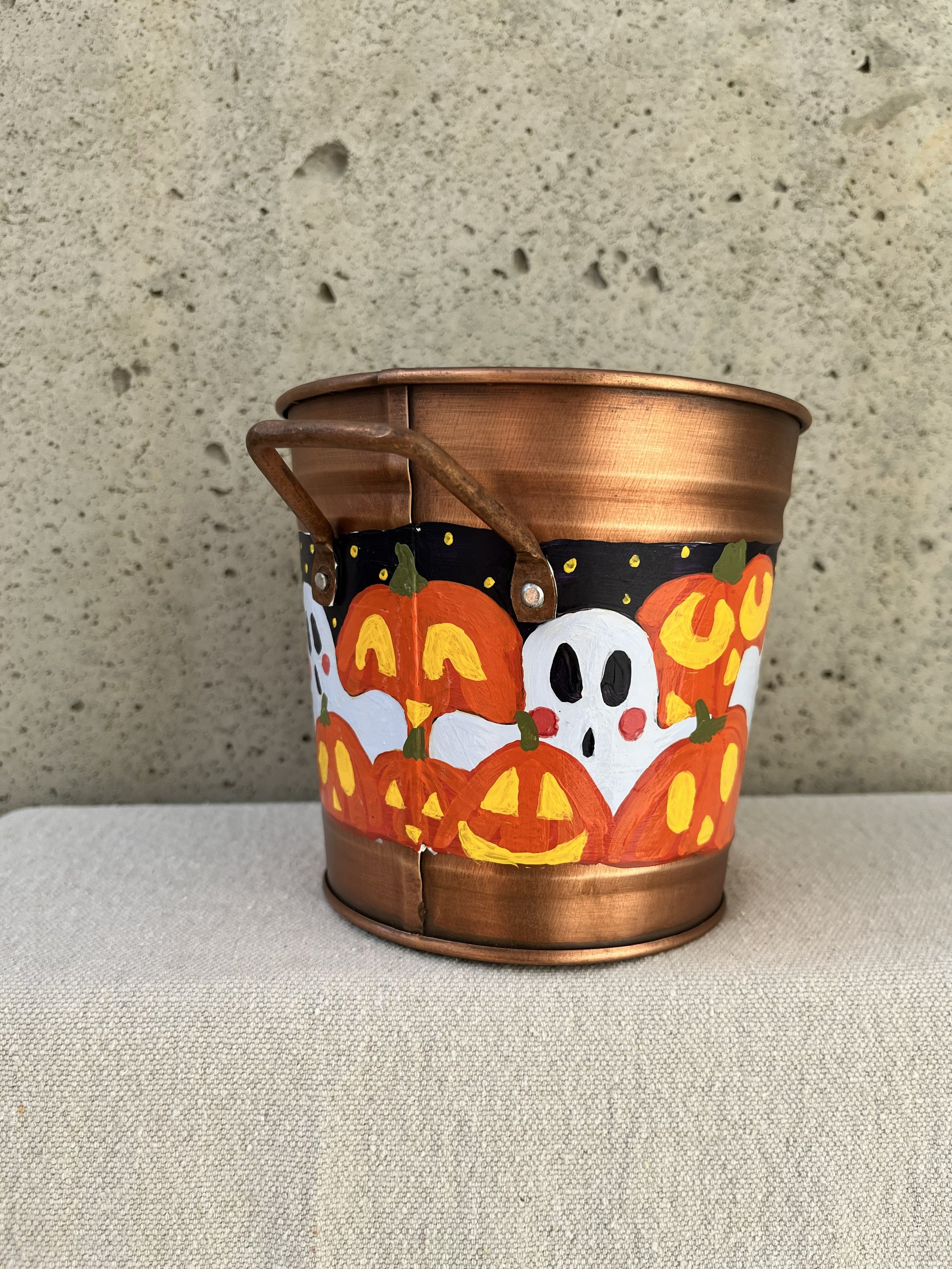 Hand painted Halloween copper color bucket. Painted with a variety of spooky ghosts and carved jack o lanterns.