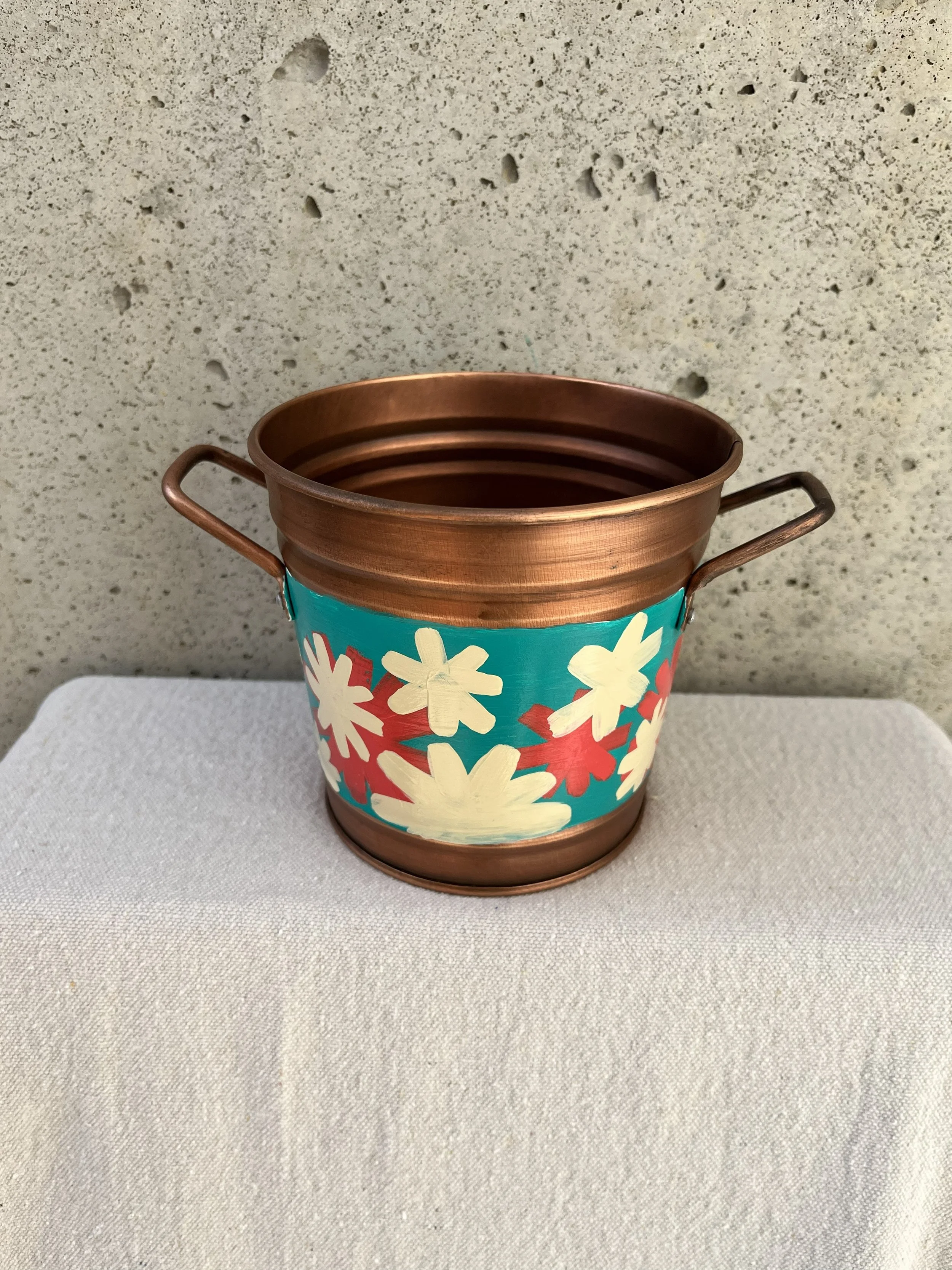 Copper color tin bucket with hand painted modern style flowers. Red, white and blue.