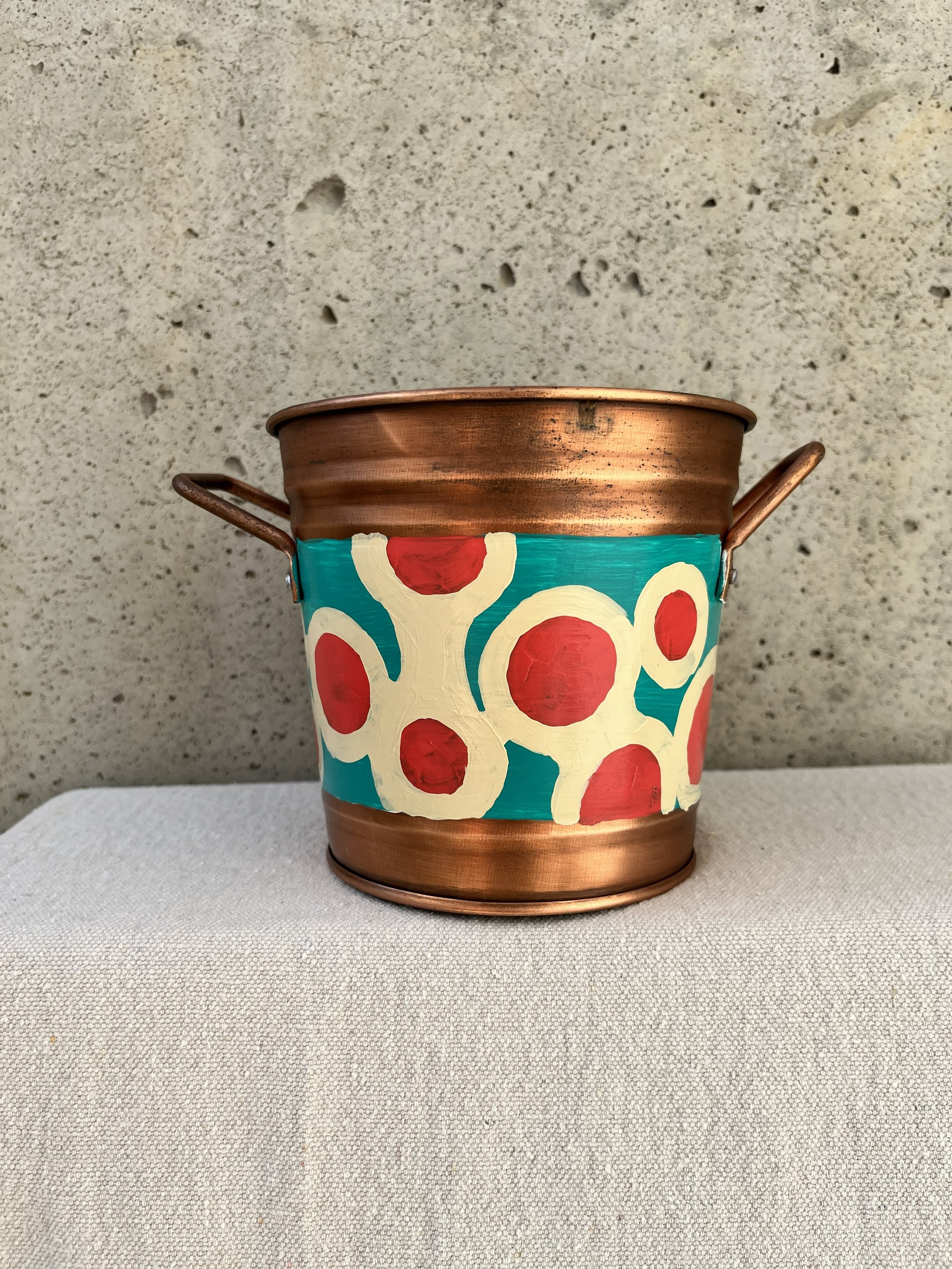 Decorative copper color tin bucket with mod circles painted on. Red, white and blue