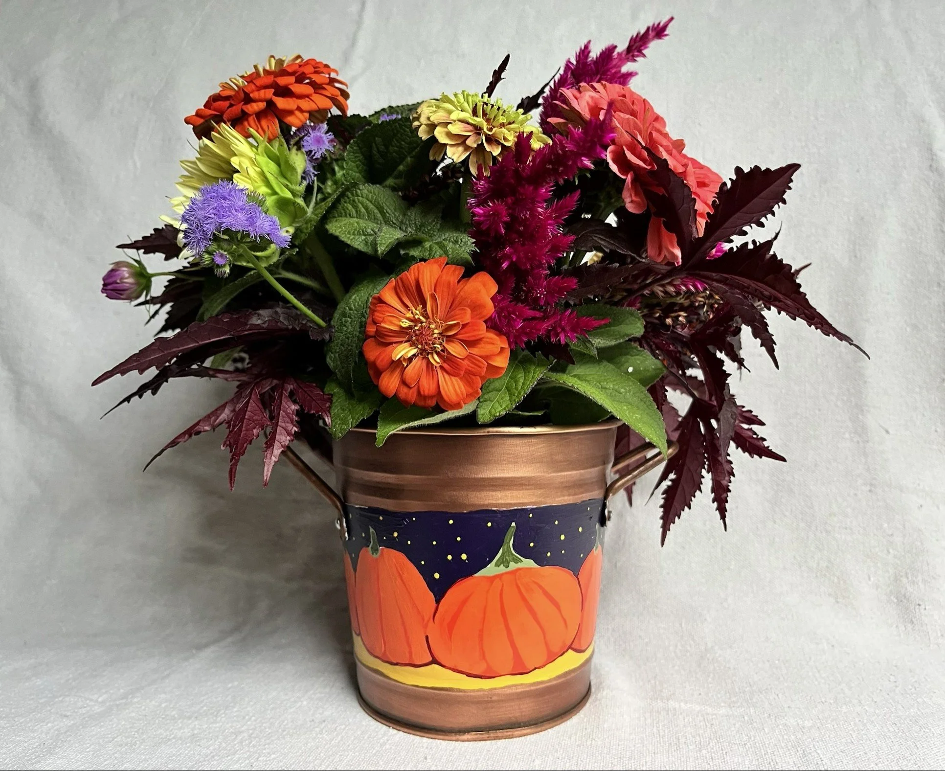 e A hand painted pumpkin patch against a starry night sky, painted on a copper color tin bucket.