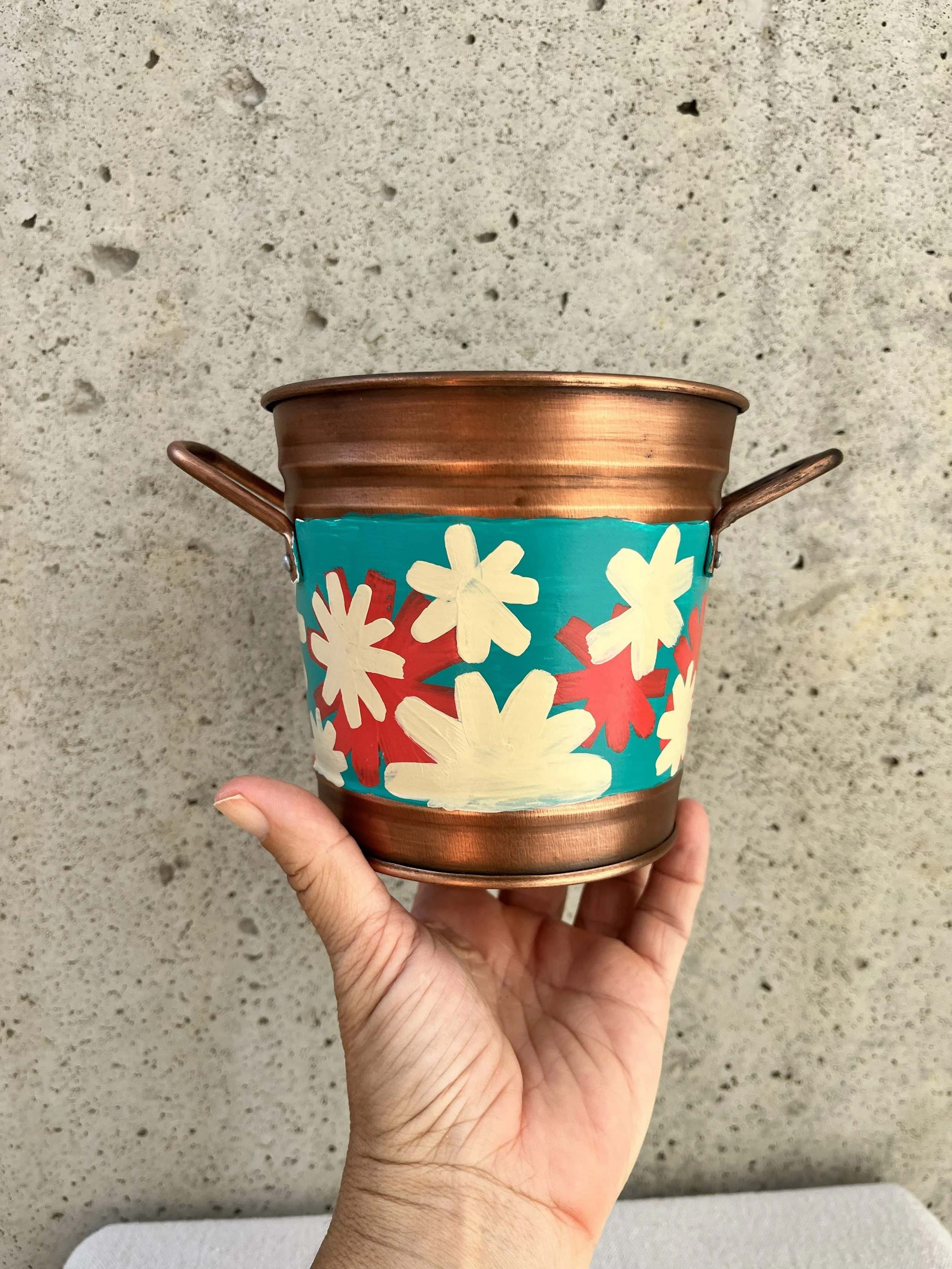 Copper color tin bucket with hand painted modern style flowers. Red, white and blue.