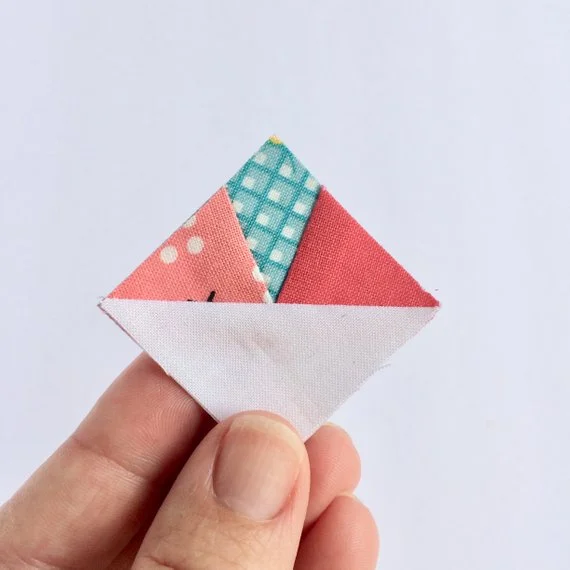 close up of fingers holding a 1%22 foundation paper pieced scrappy triangle.jpg
