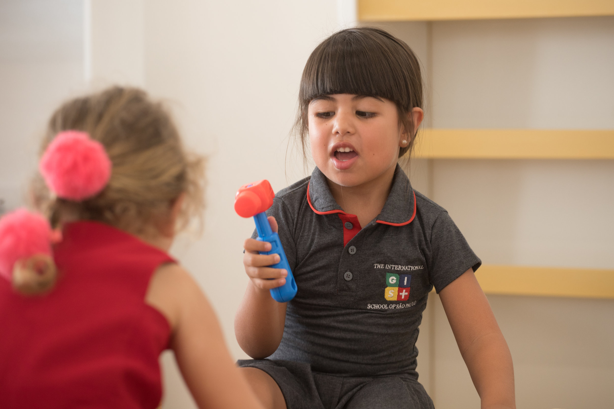 Student wears a short-sleeved gray polo dress with the GIS SP logo, one of the school uniform pieces.