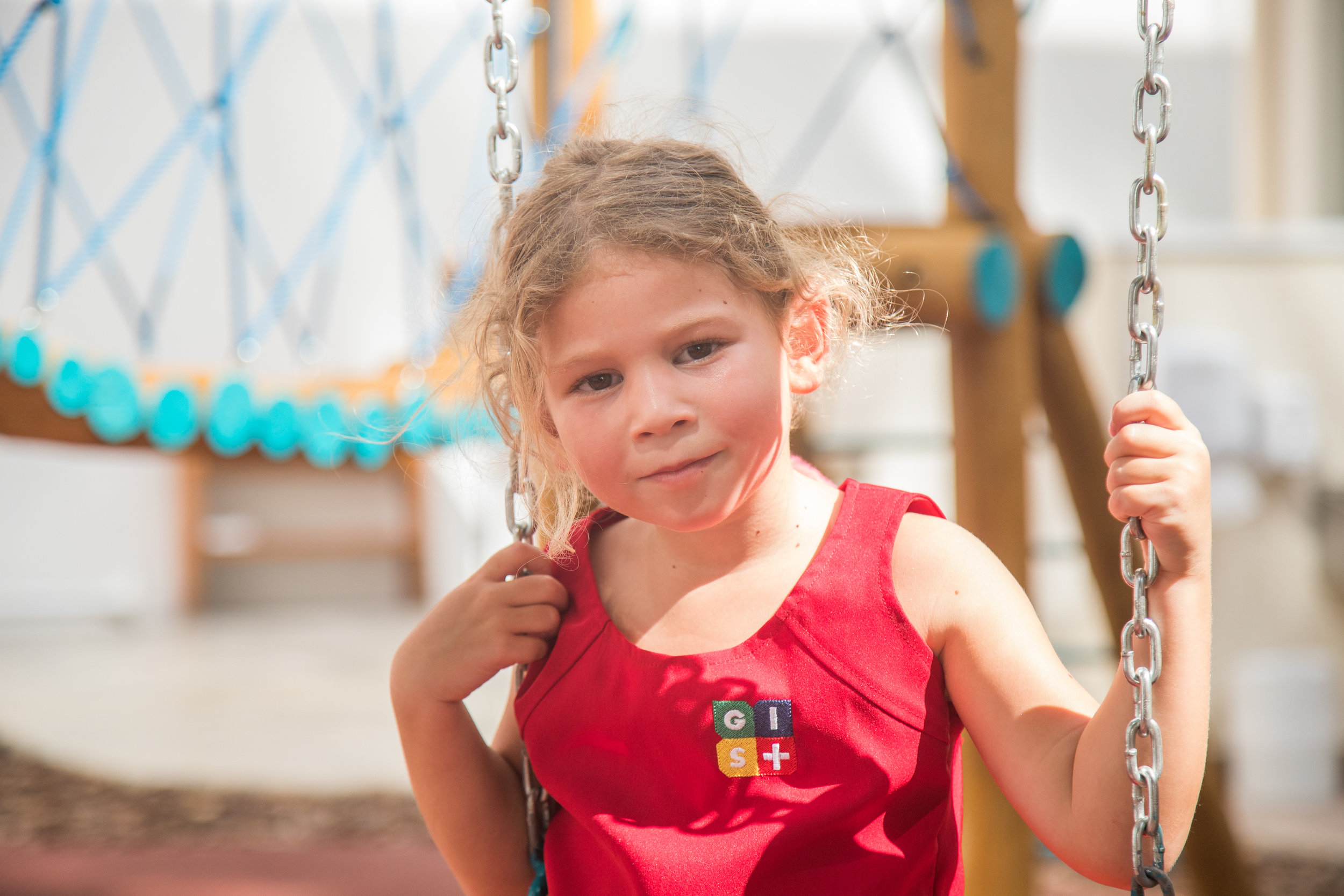 Student wears a red tank top dress with the GIS SP logo, one of the school uniform pieces.