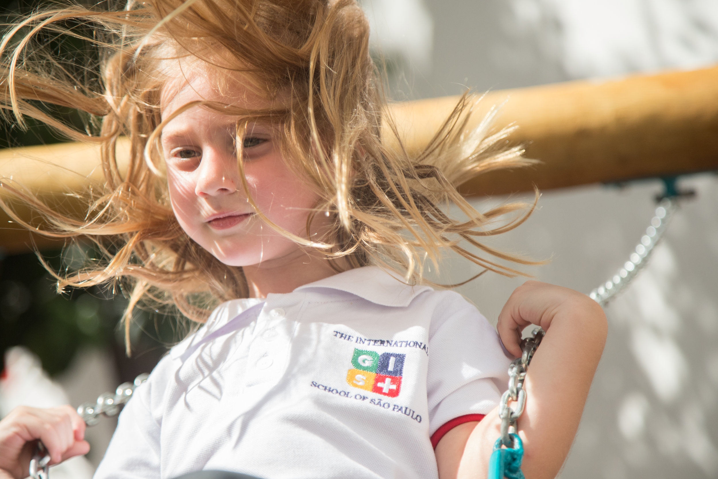 Student on school swing wears white short-sleeved polo shirt with red details.