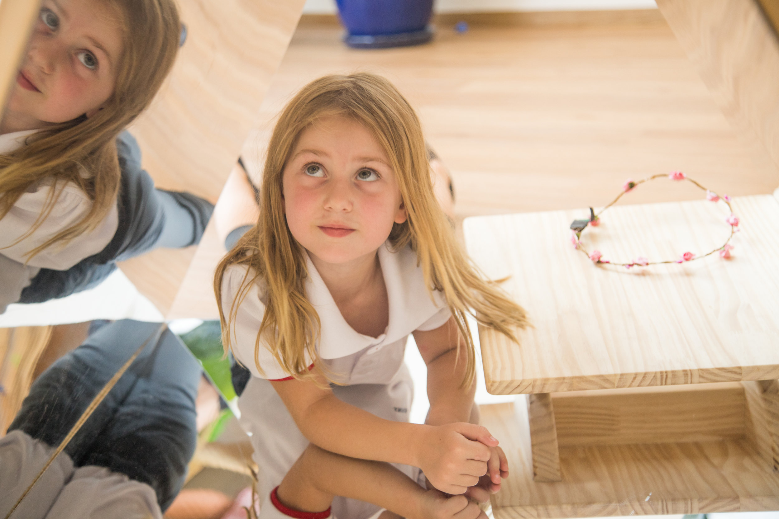 A student in activity with mirrors wears a white short-sleeved polo shirt, one of the school uniform pieces.