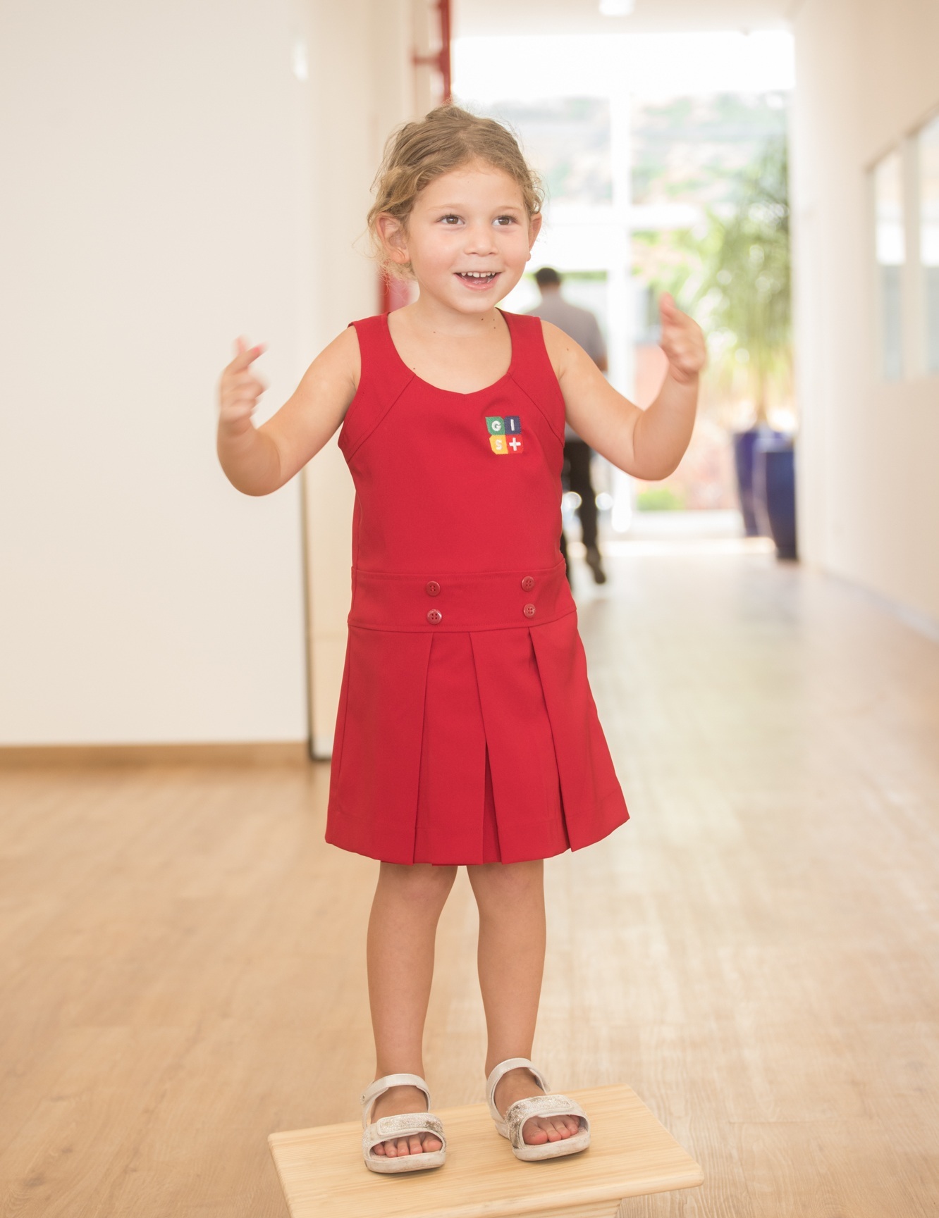 Student wears a red tank top dress with pleated skirt and button details, one of the school's uniform options.