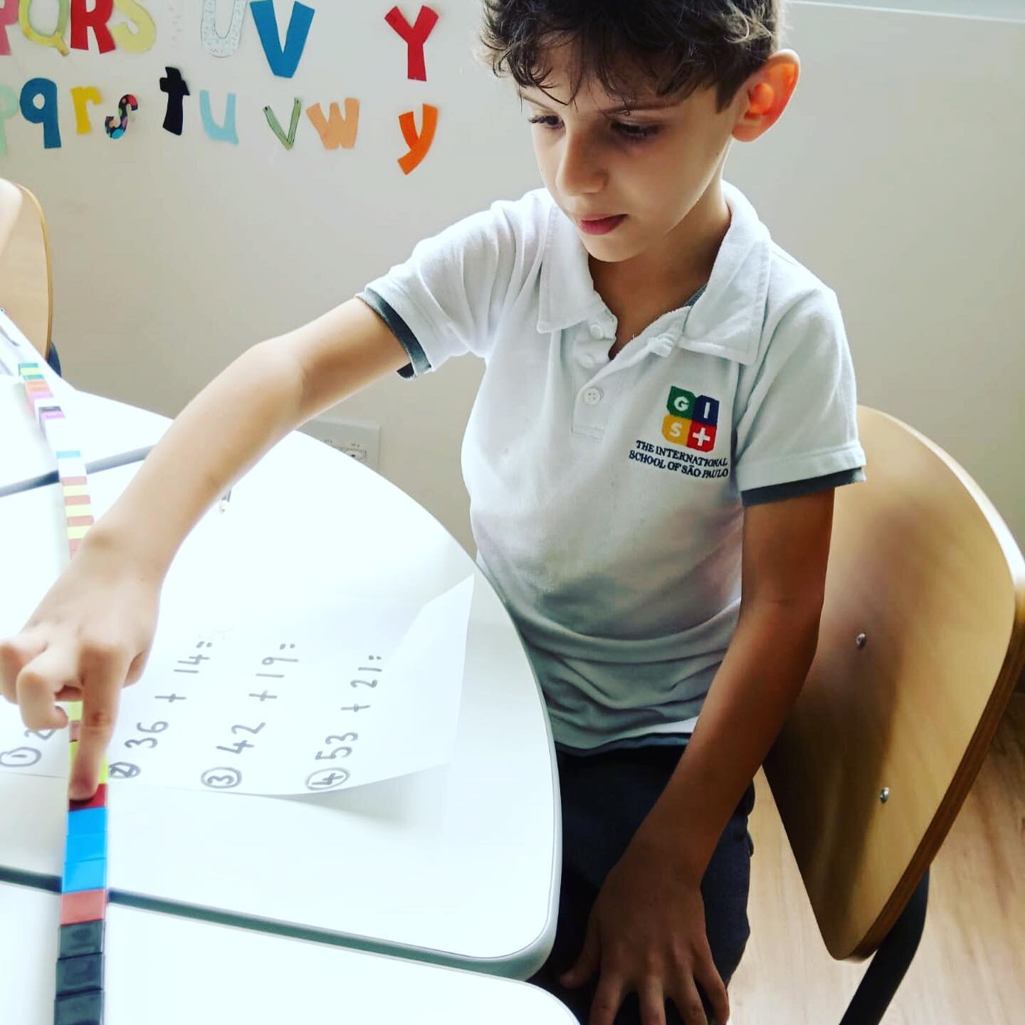 Student in mathematical activity that mixes numbers and colored blocks arranged on the table.