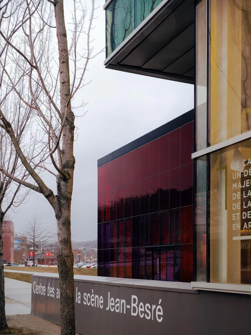 Close-up view of the architectural connection between the modern red glass volume of Le Grand-Espace and the adjacent production arts building CASJB.