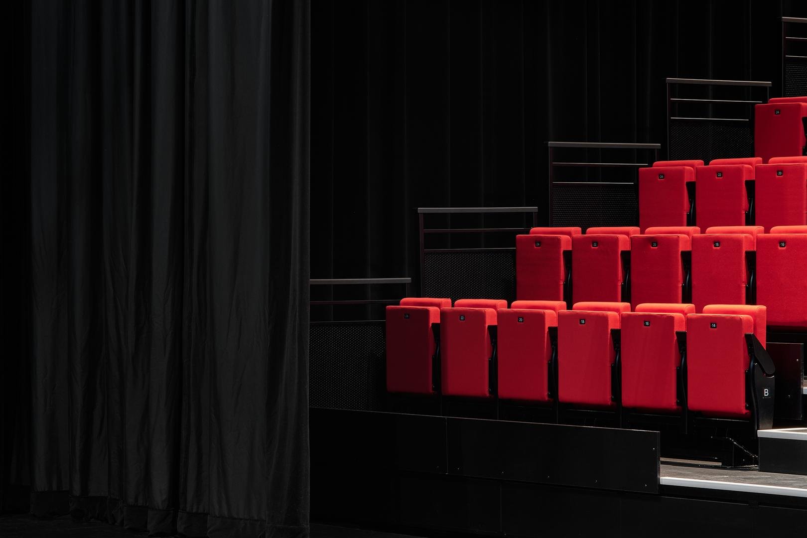 Architectural close-up profile of the modern red theater seats on the retractable bleacher system inside Le Grand-Espace.
