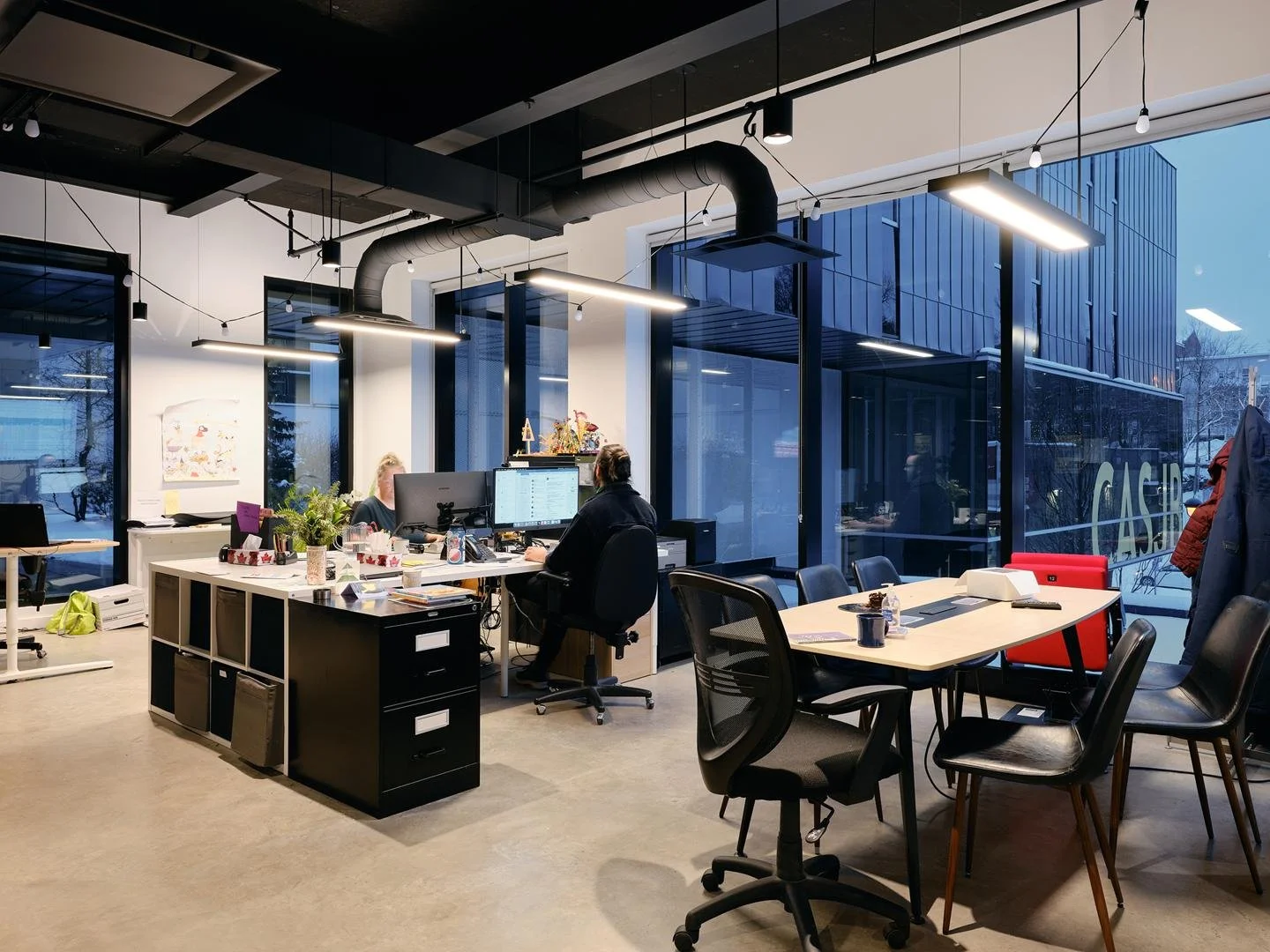 Bright open-plan administrative office space inside Le Grand-Espace, with large windows overlooking the street.