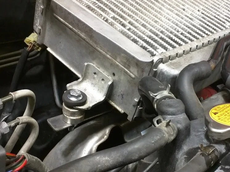 My leftover piece of metal with a couple holes drilled in it do the trick. Bolted to the factory mount and extending out just far enough. I had a lost the rubber isolator bushing in this photo.