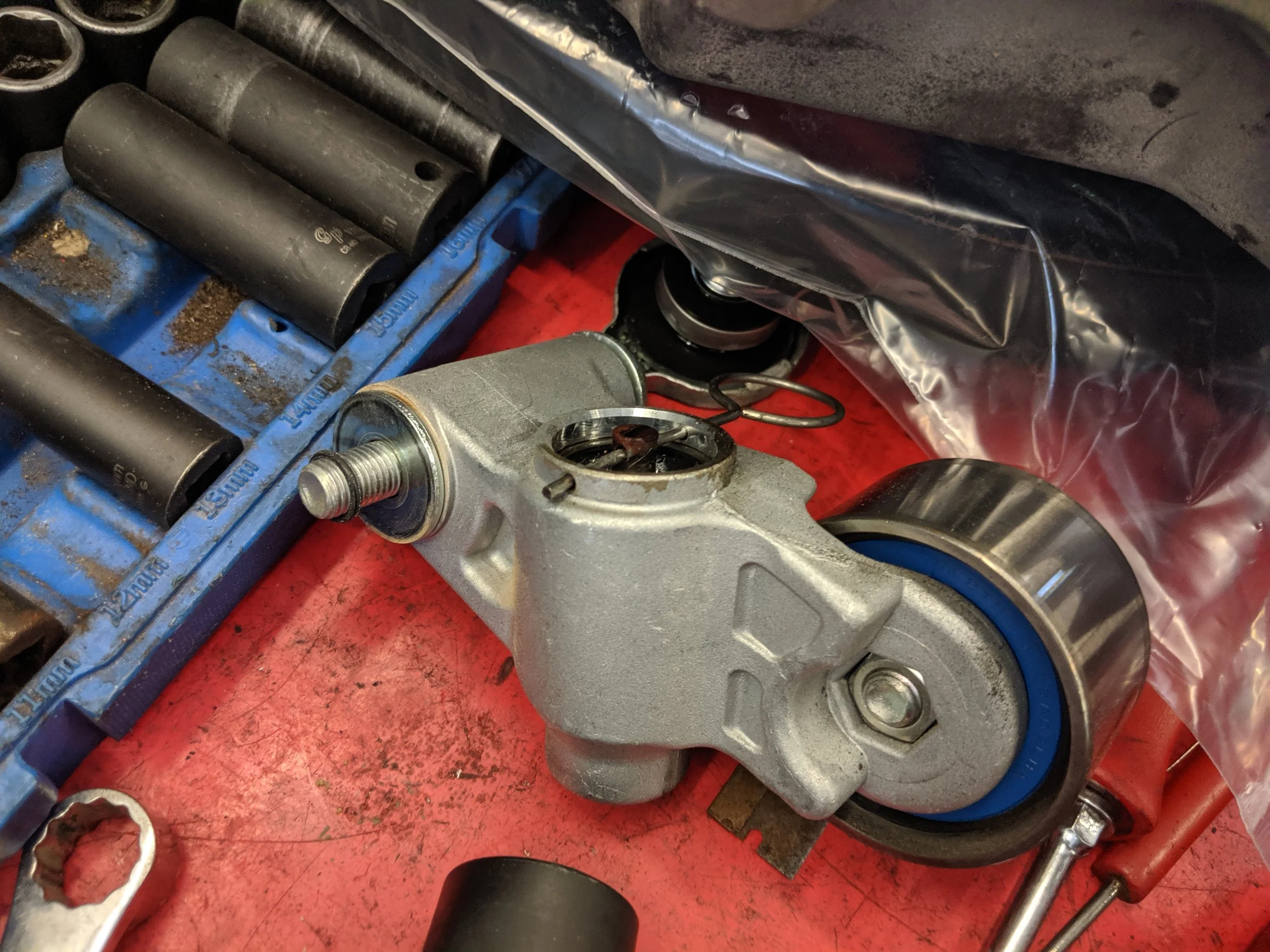 With the tensioner off the car, slowly compressing the tensioner to install the pin back within it.