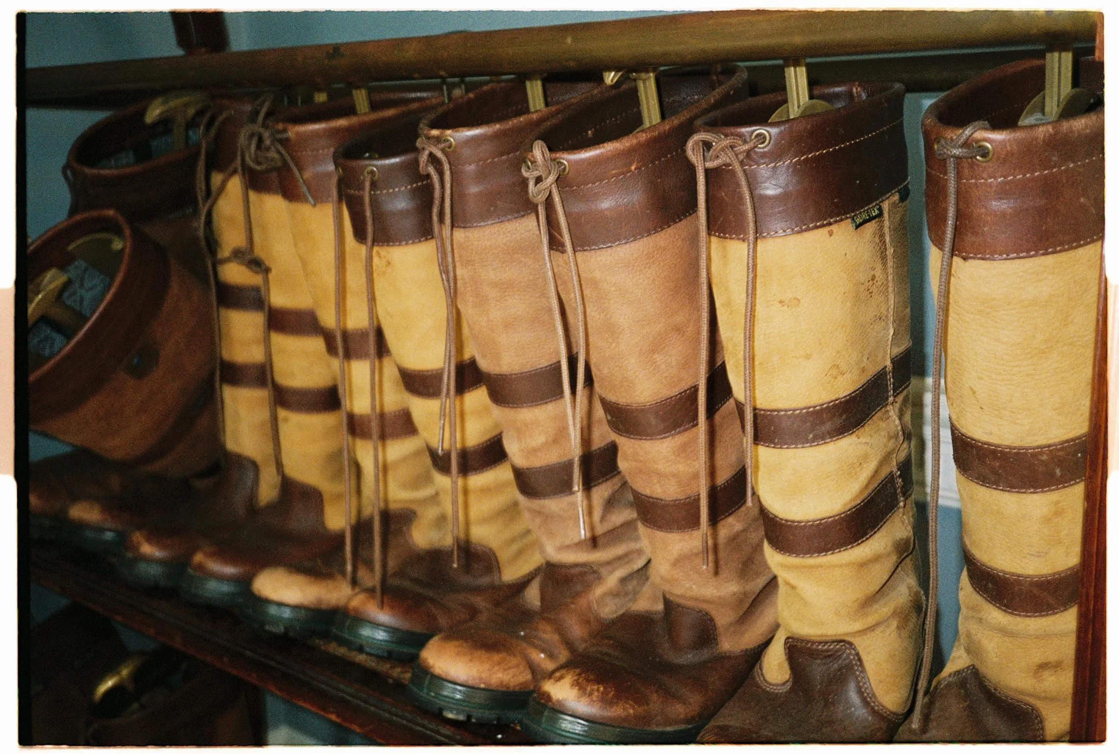 A row of vintage leather cowboy boots in brown and tan colors on a shelf.