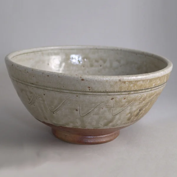 The perfect bowl for your breakfast cereal or soup. Lifted on a turned foot ring this is decorated with an incised wave pattern. The larger size would take a full meal (“The Buddha Bowl”).