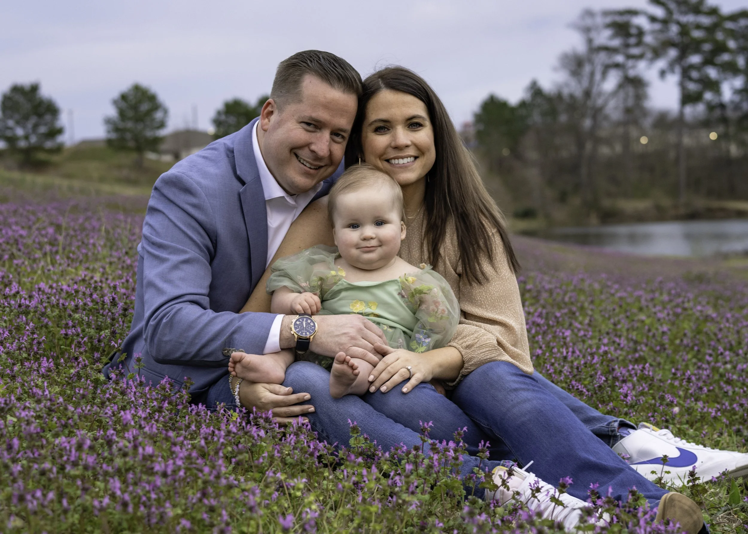Family of 3 sitting a  field of purple flowers