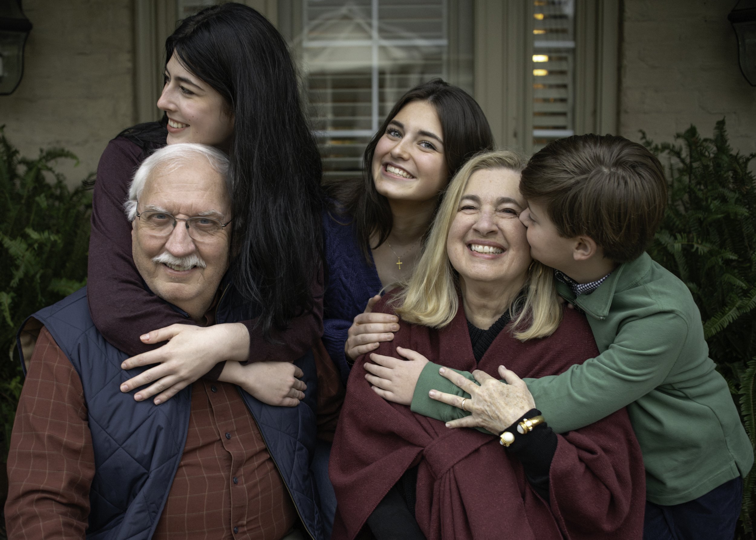 Grandparents hugging their grown children during a photo session