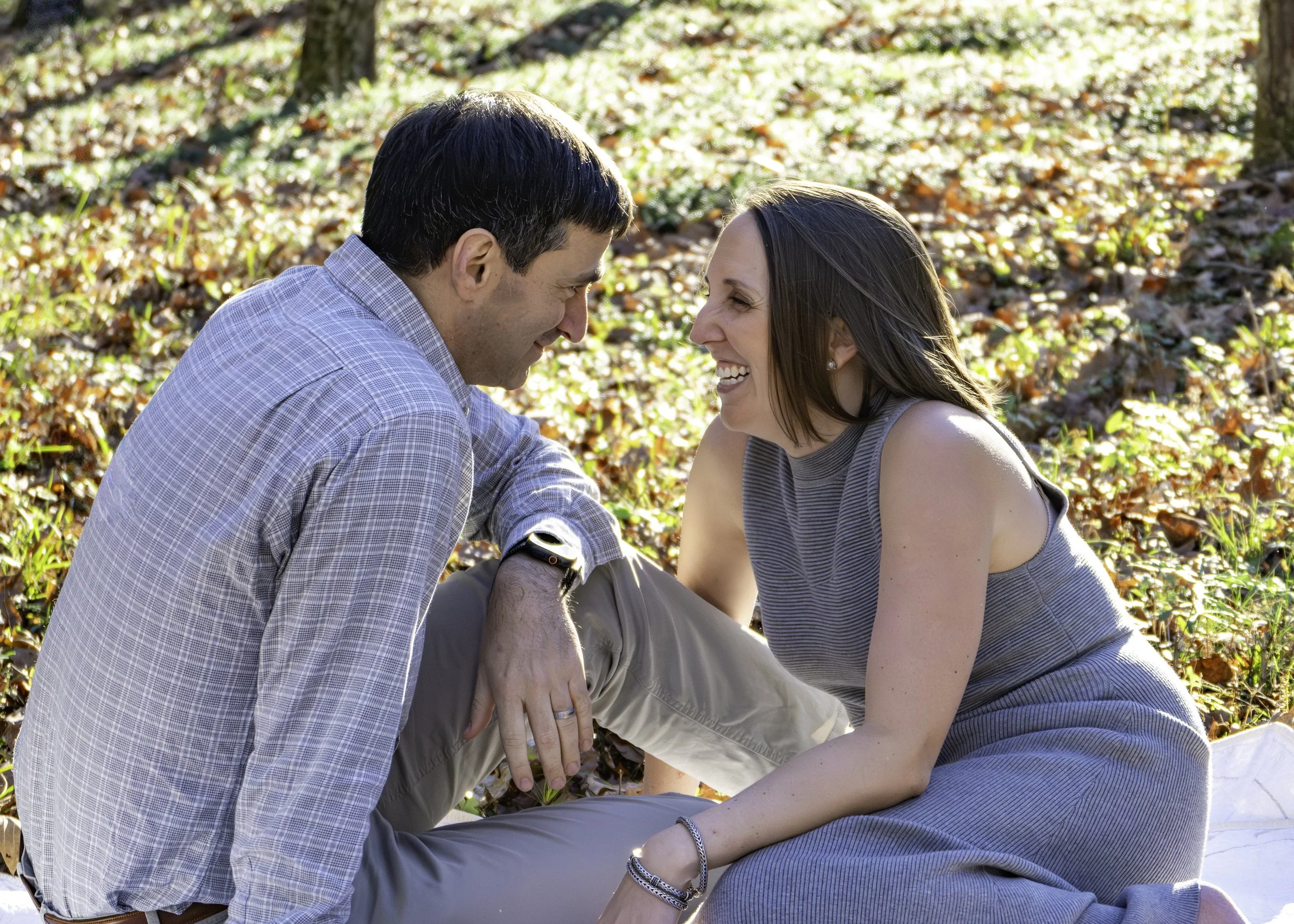 Husband and wife sharing a laugh together while sitting on a blanket during their family photography session.