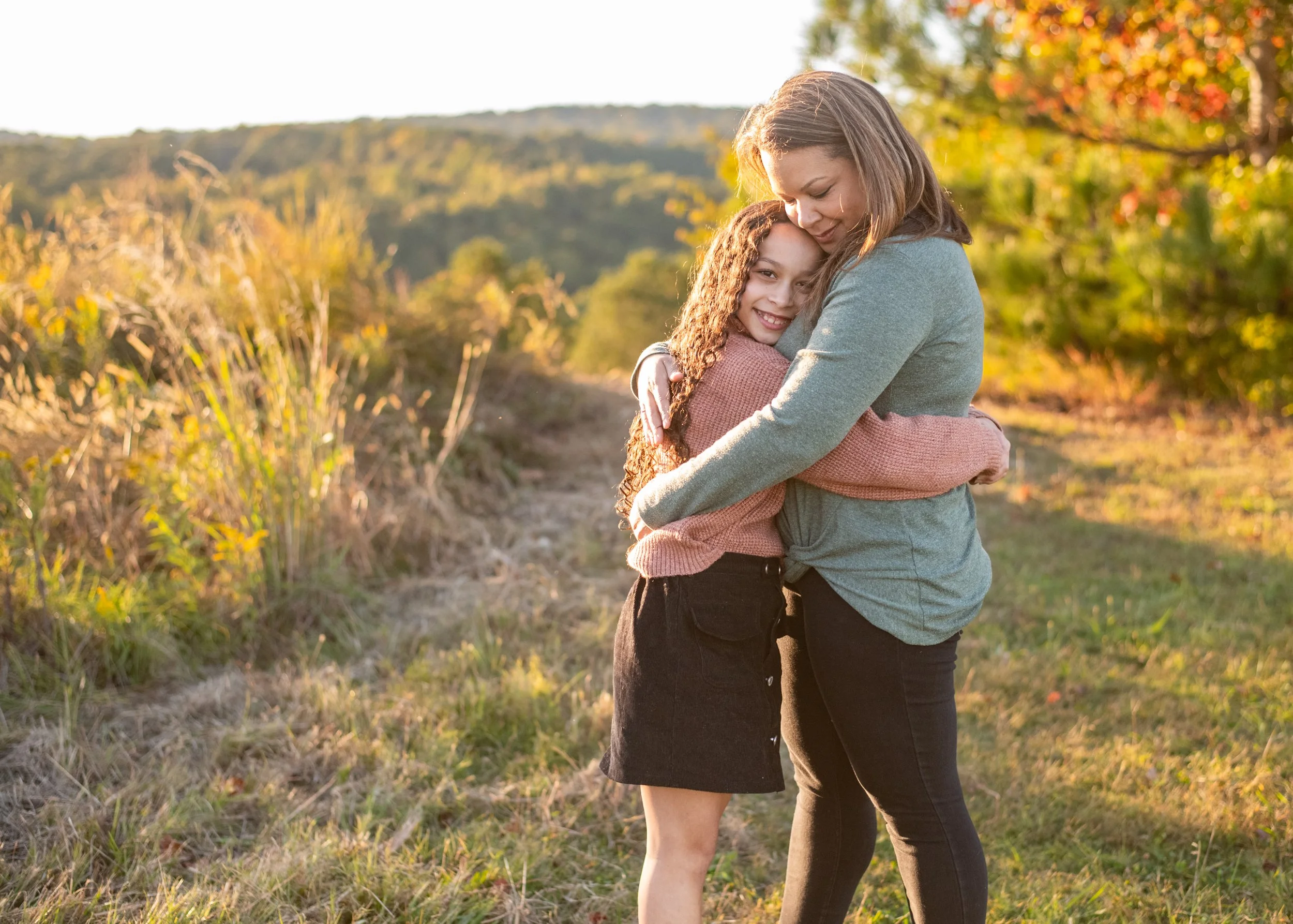 Family photo of mom and daughter hugging in a field. family photographer near me