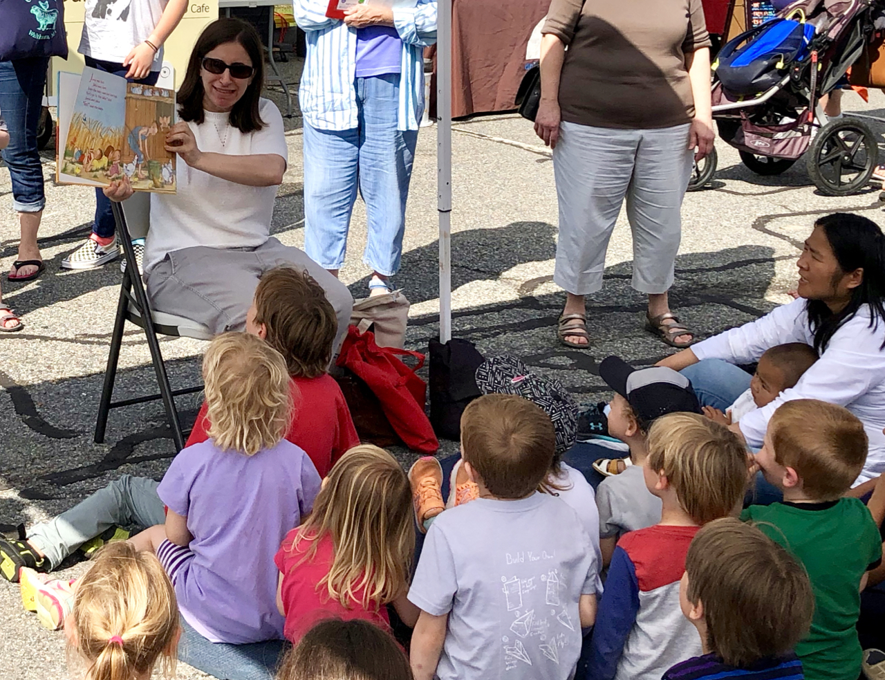 A woman showing a book to a group of kids