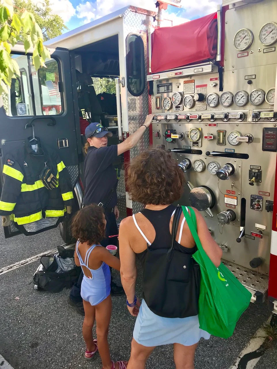 A firefighter showing a child and adult her equipment