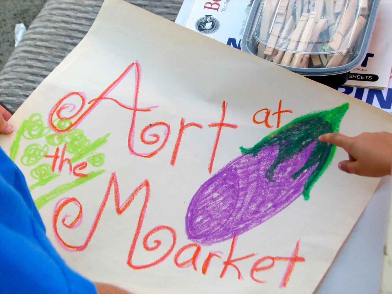 A sign that says "Art at the Market" with a drawing of an eggplant