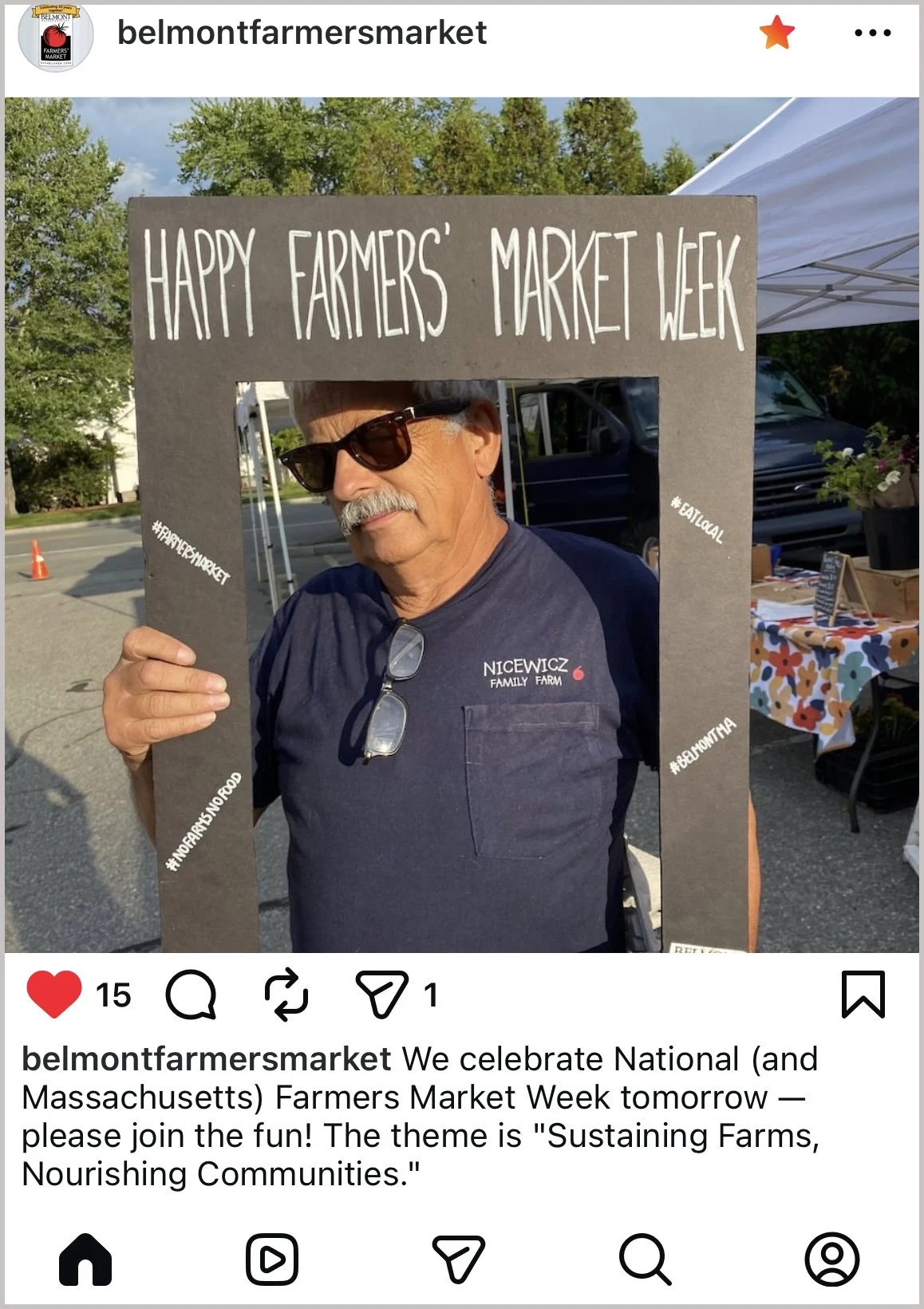 A man in sunglasses holding a cardboard frame that says Happy Farmers' Market Week