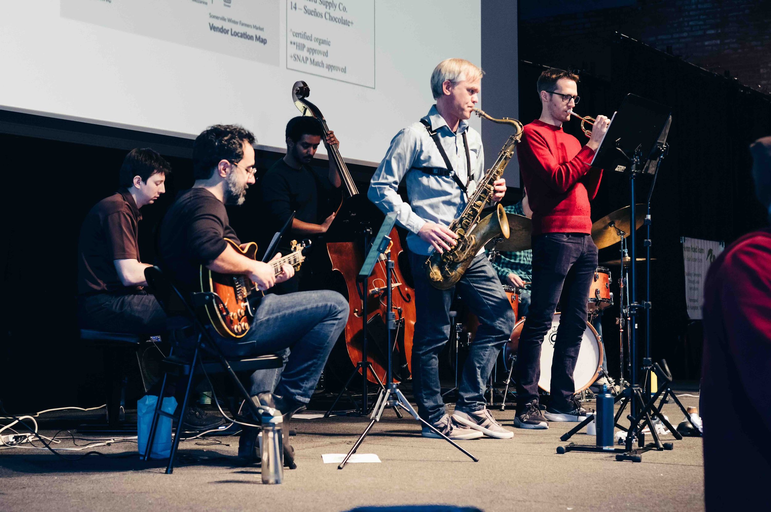 Five performers on various instruments on a stage