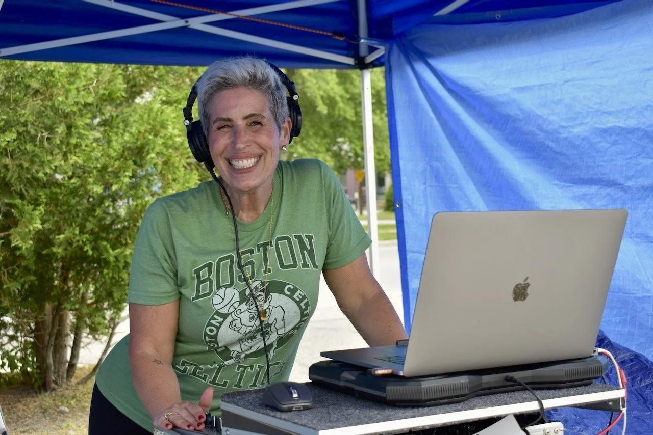 A woman wearing headphones in front of a laptop computer, outdoors
