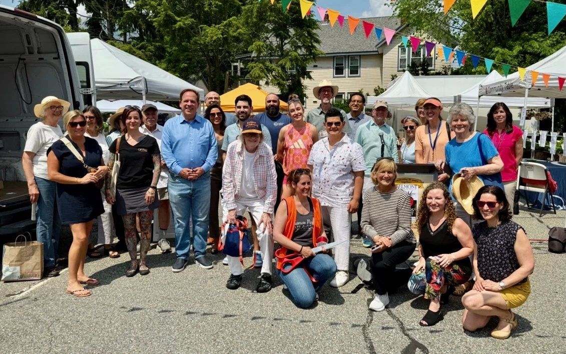 A group of people standing and kneeling in a parking lot where the Market is held