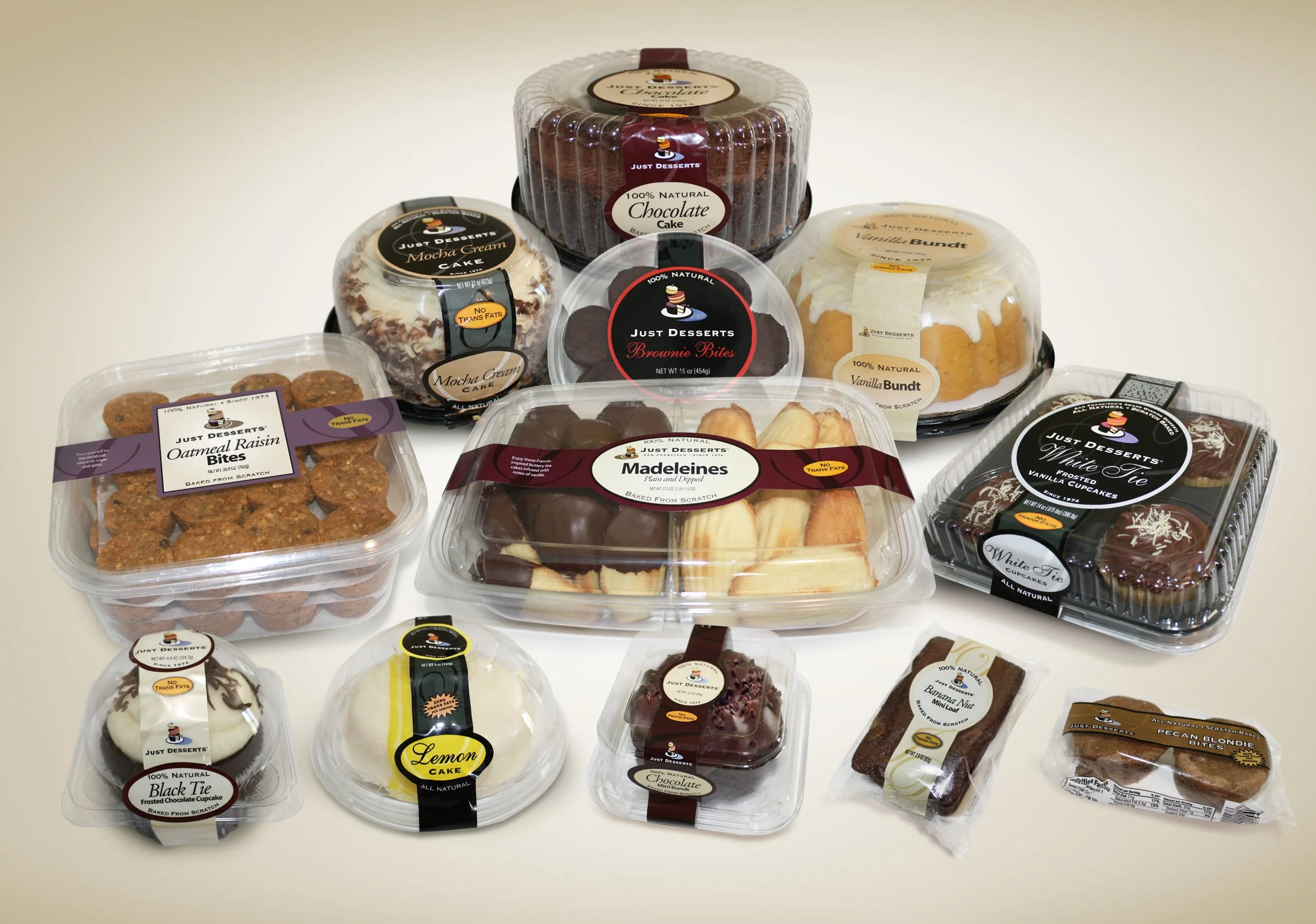 Assortment of various desserts including cupcakes, cookies, brownies, cake rolls, and other baked treats in clear plastic containers with labels.