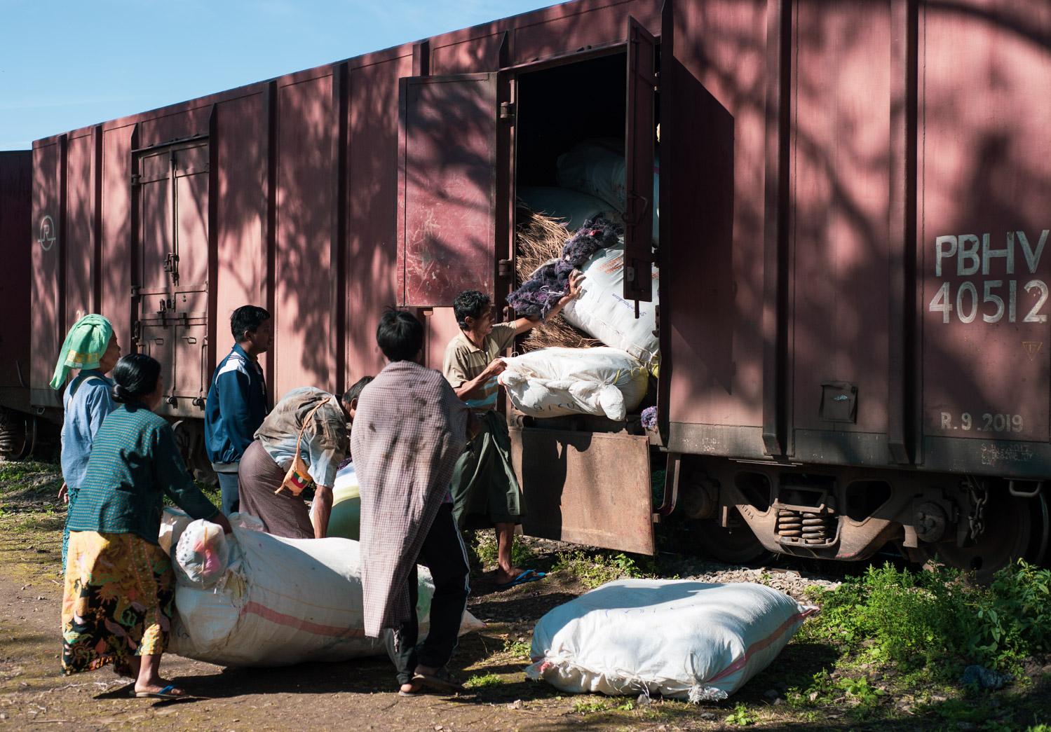 Unloading bags of straw from the Mandalay-Lashio train.
