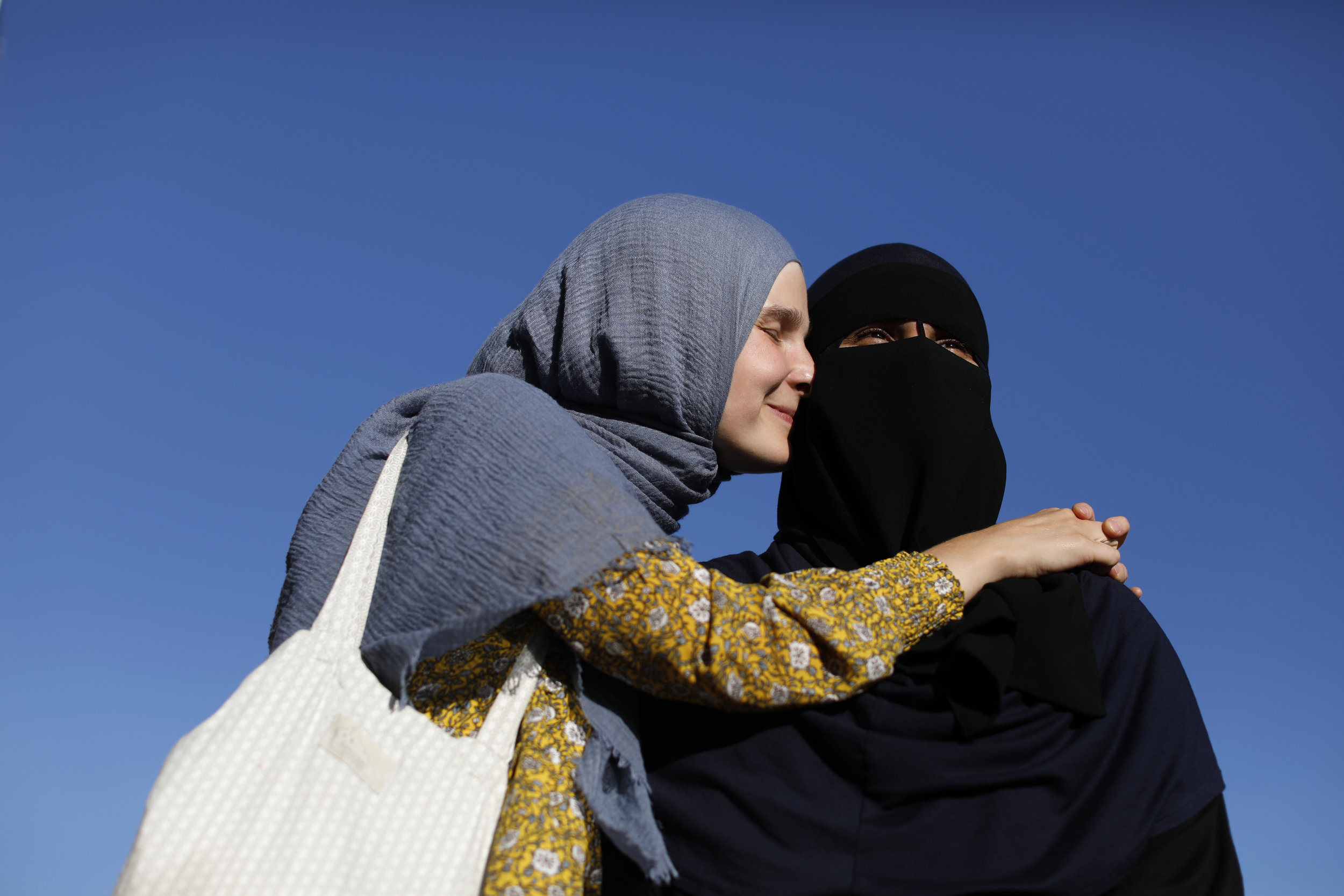 Natacha and Nayab stand beside the apartment complex that Natacha calls home. Natacha converted to Islam, the faith of her husband.