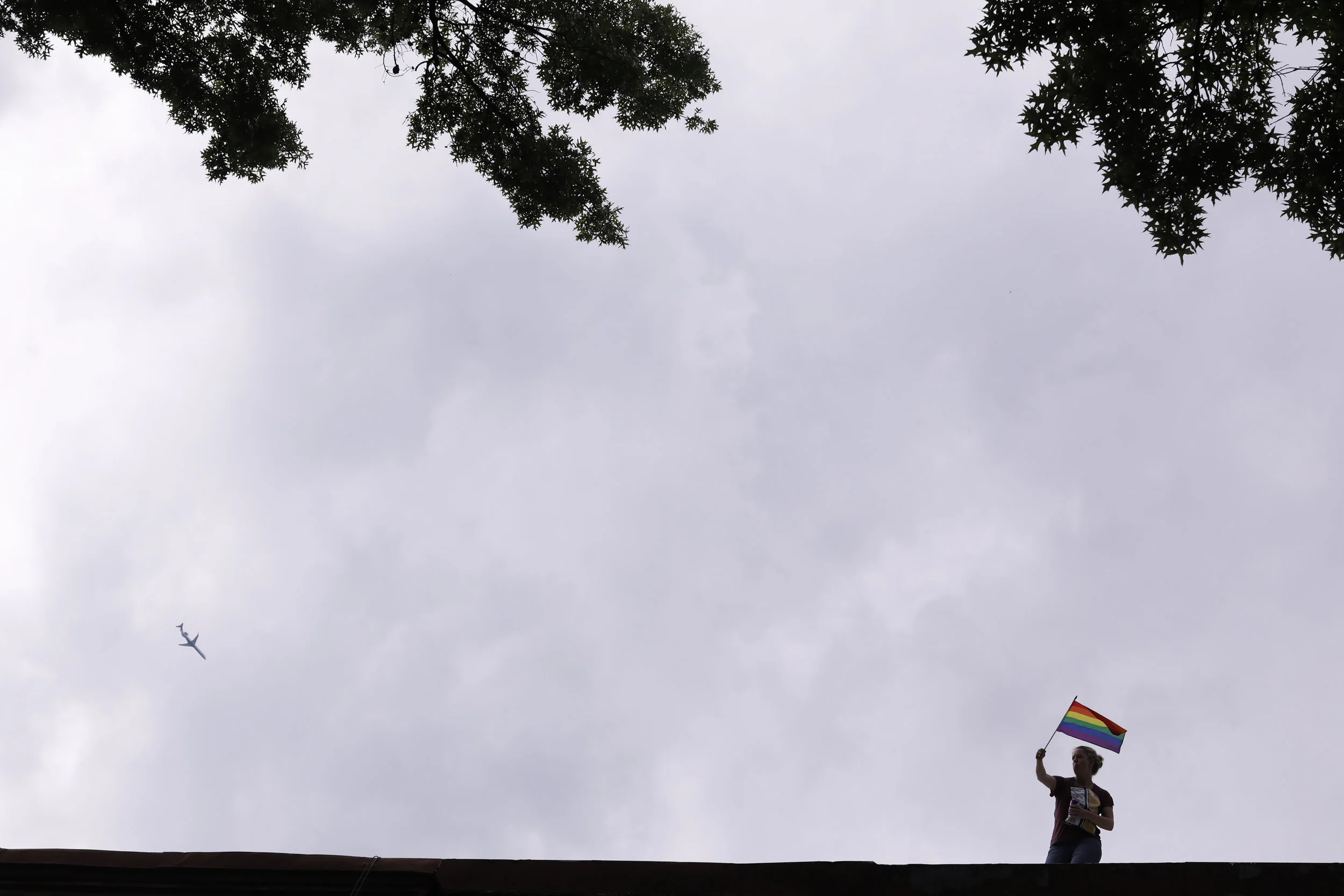 A person waves a flag from a rooftop during the Pride Parade. 2018.