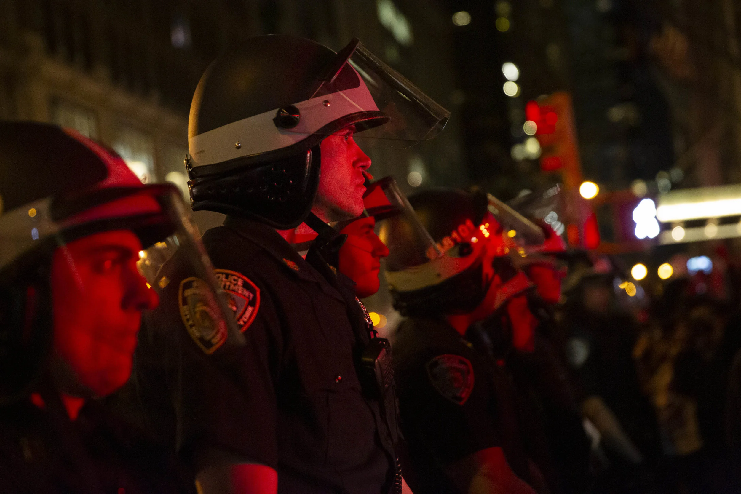  Police officers in riot gear line a street in Manhattan as protesters gather.  