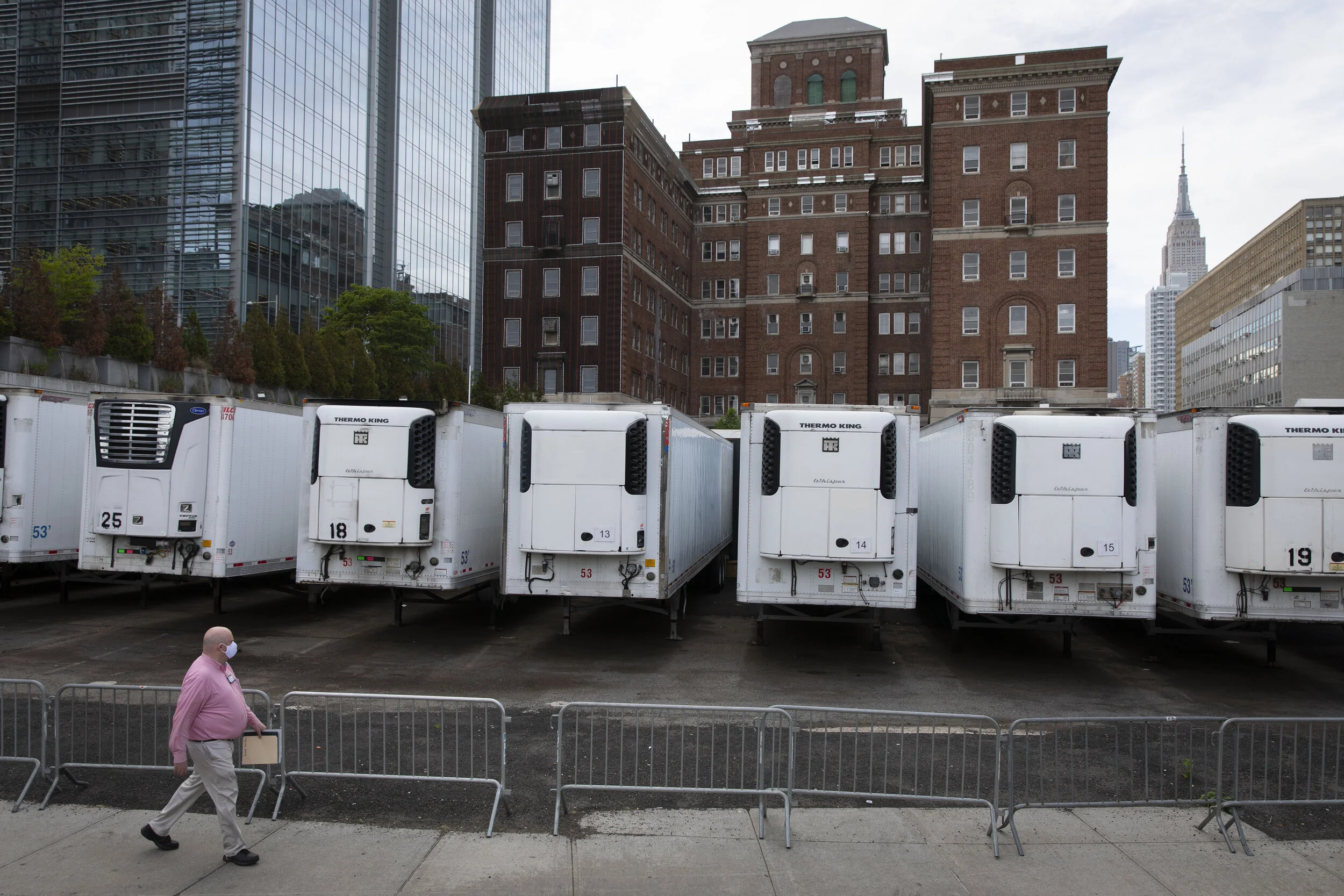  A person walks by a row of refrigerated trucks that act as temporary morgues at the rear of the Office of Chief Medical Examiner of the City of New York. The refrigerated trucks became fixtures outside of medical centers to deal with the overflow of