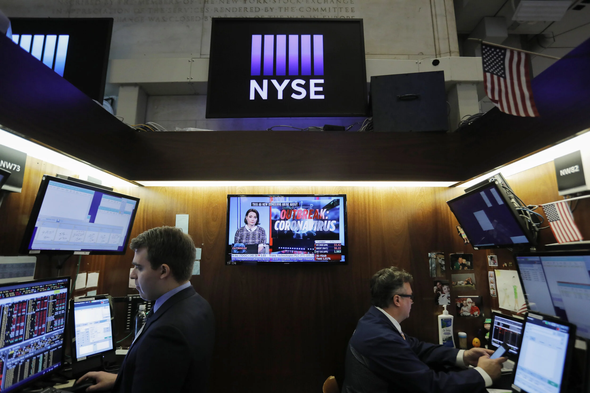  Traders work on the floor of the New York Stock Exchange as a news broadcast discusses the outbreak of coronavirus. The trading floor closed on March 20 after several traders and members of the media contracted the illness, eventually re-opening aga