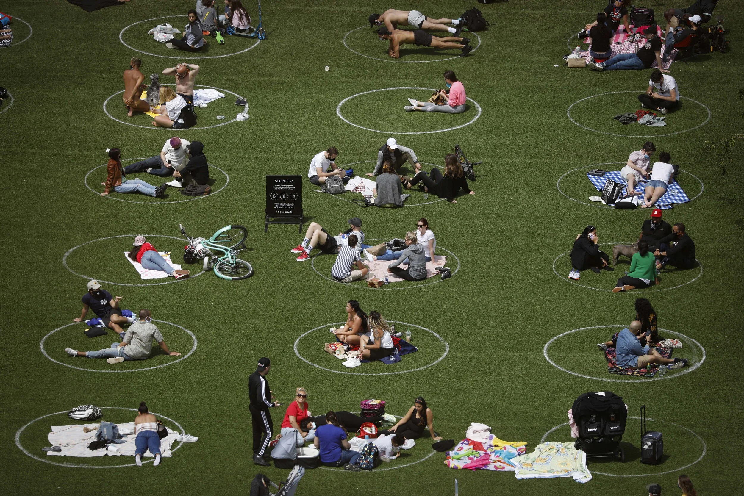  People sit in circles painted on a lawn in Domino Park, Brooklyn. The circles were painted to encourage the act of social distancing, thought to be a method of preventing the spread of coronavirus.  